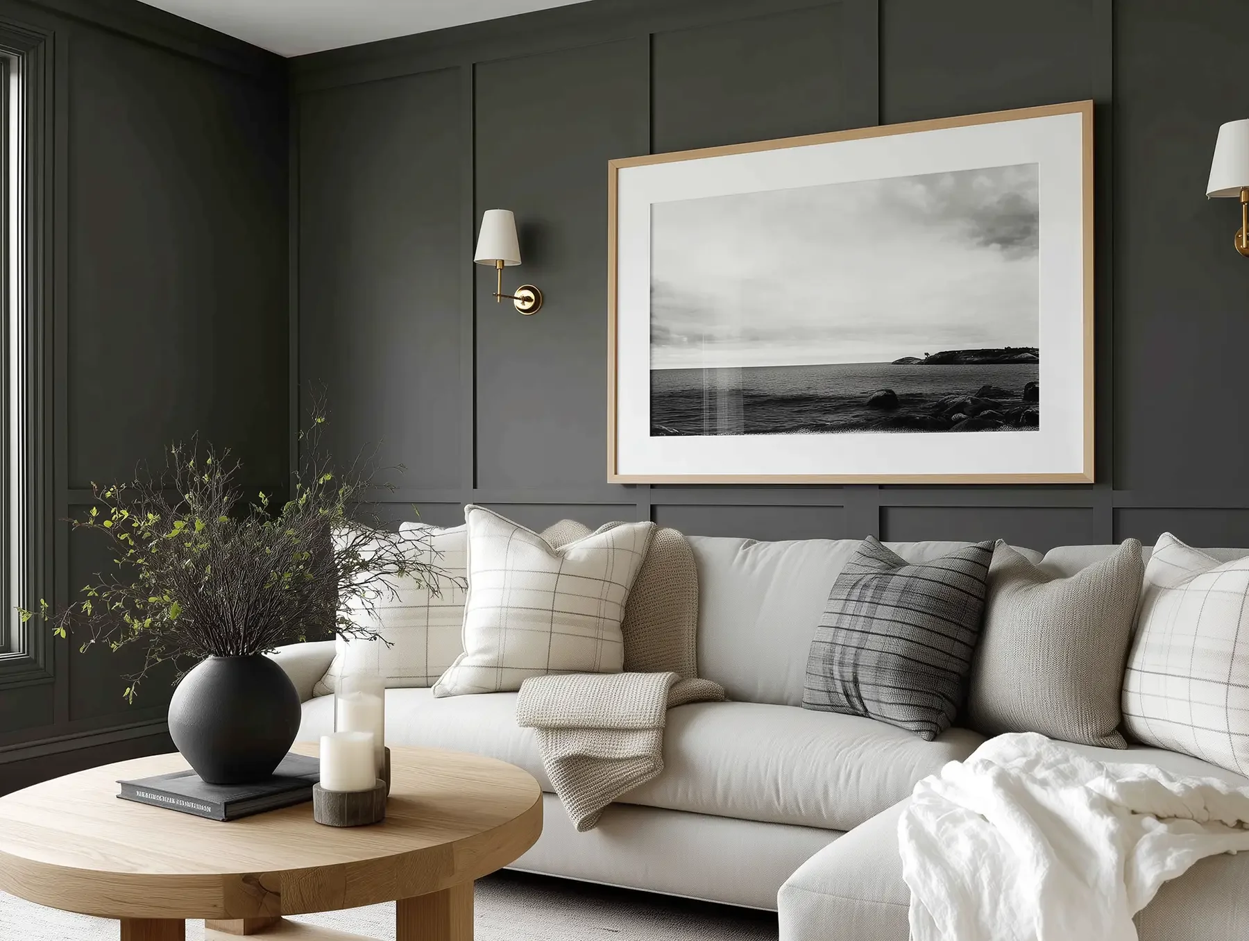 Modern living room in Dubai by Studio Sakaia with dark gray paneled walls, white sofa, oak coffee table and framed black-and-white artwork.