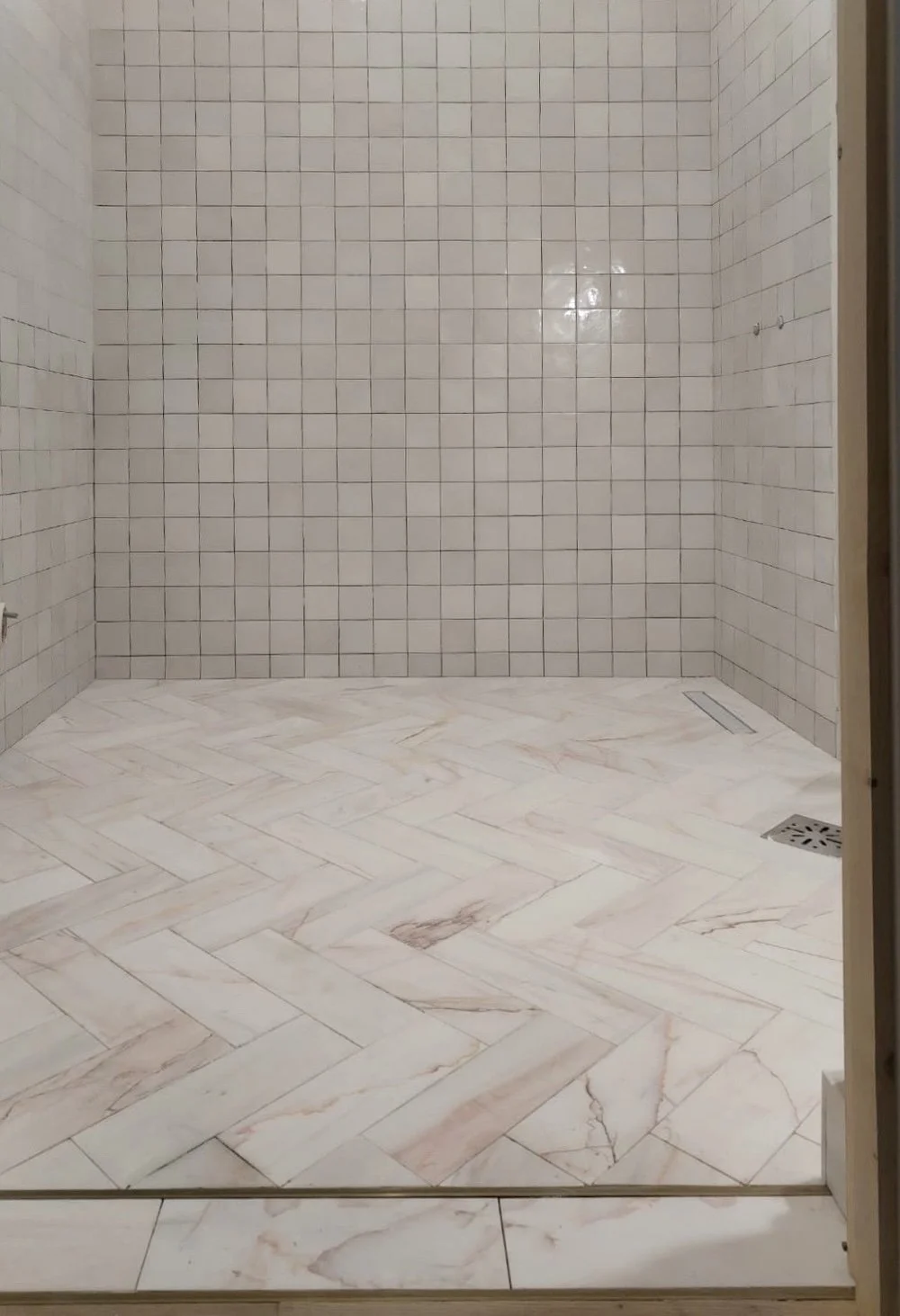 Studio Sakaia bathroom with marble herringbone floor and Moroccan zellige tile shower walls, blending soft blush veining with artisanal texture.