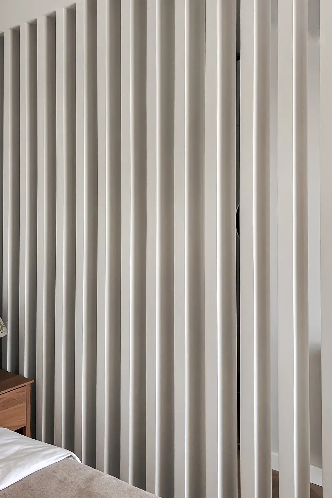 Vertical white slat divider in a modern interior, adding texture and architectural rhythm, by Studio Sakaia.