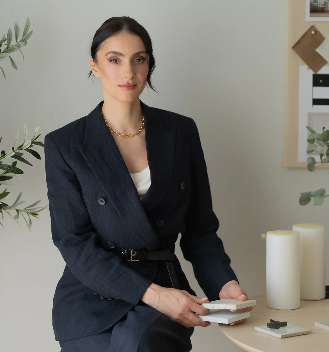 Madalina Aris, Creative Director of Studio Sakaia, in a modern minimalist setting with candles, plants, and design materials on the table.