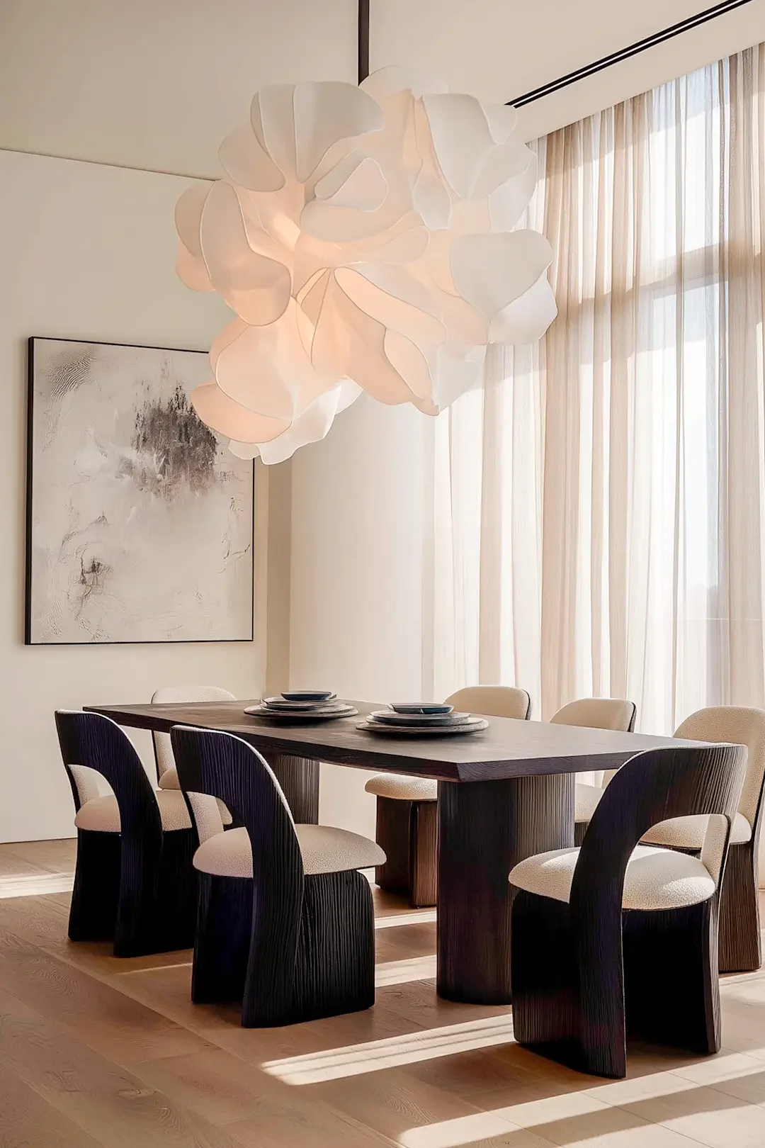 Modern dining room by Studio Sakaia with dark wood table, sculptural pendant light and sunlight filtering through sheer curtains.
