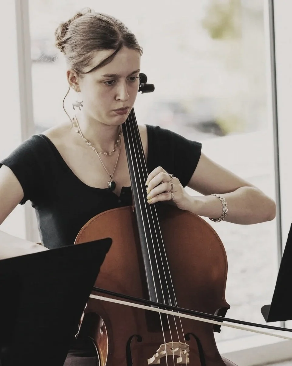 Young girl playing the cello while reading sheet music.
