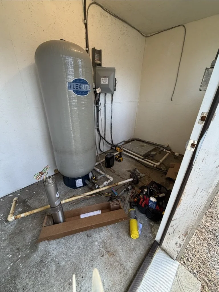 A utility room with plumbing and electrical equipment, including a large gray Flex-Lite water filter tank, pipes, tools, and an electrical panel in eagle point