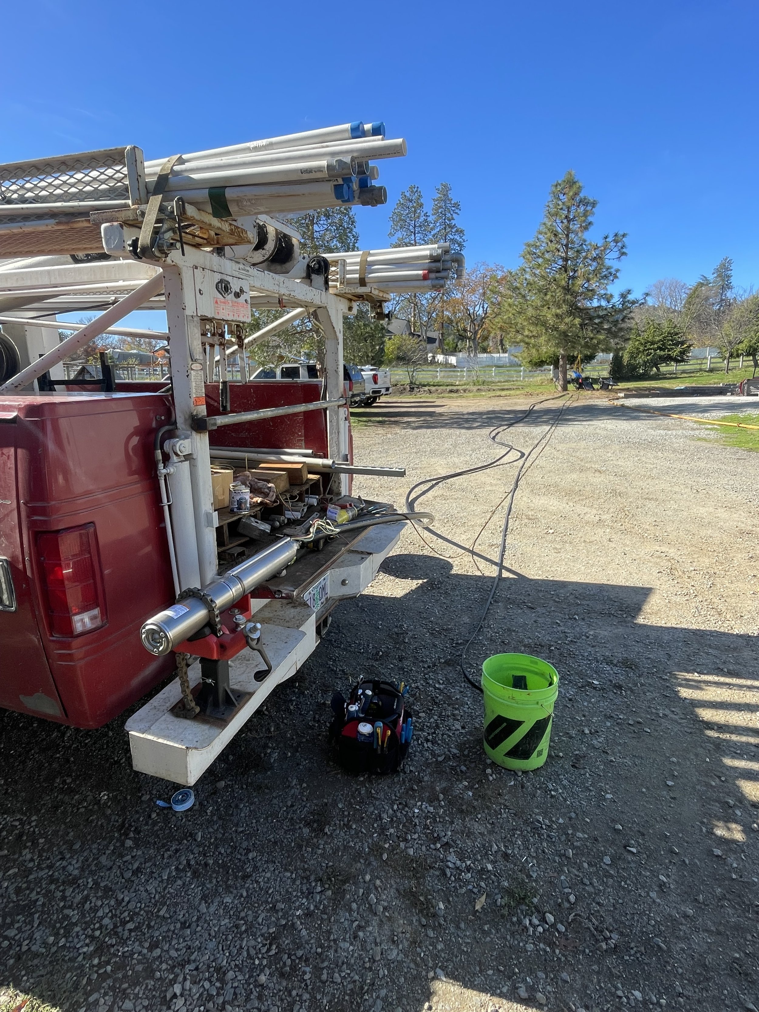red well pump hoist truck, with a well pump and motor with back poly pipe and flat jacket wire. Getting ready to put down a well