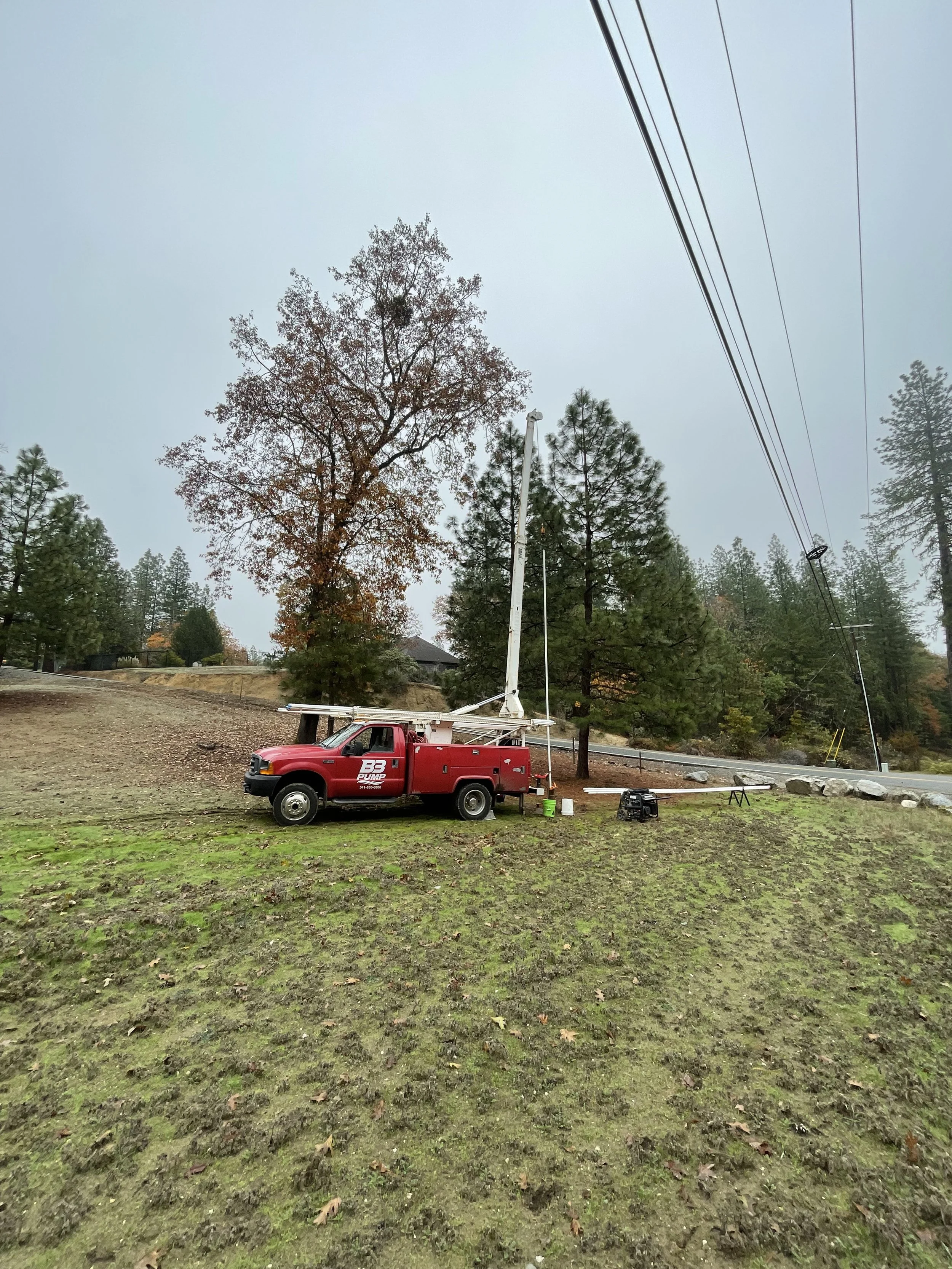 A red well pump hoist truck setting a well pump for a well flow test 