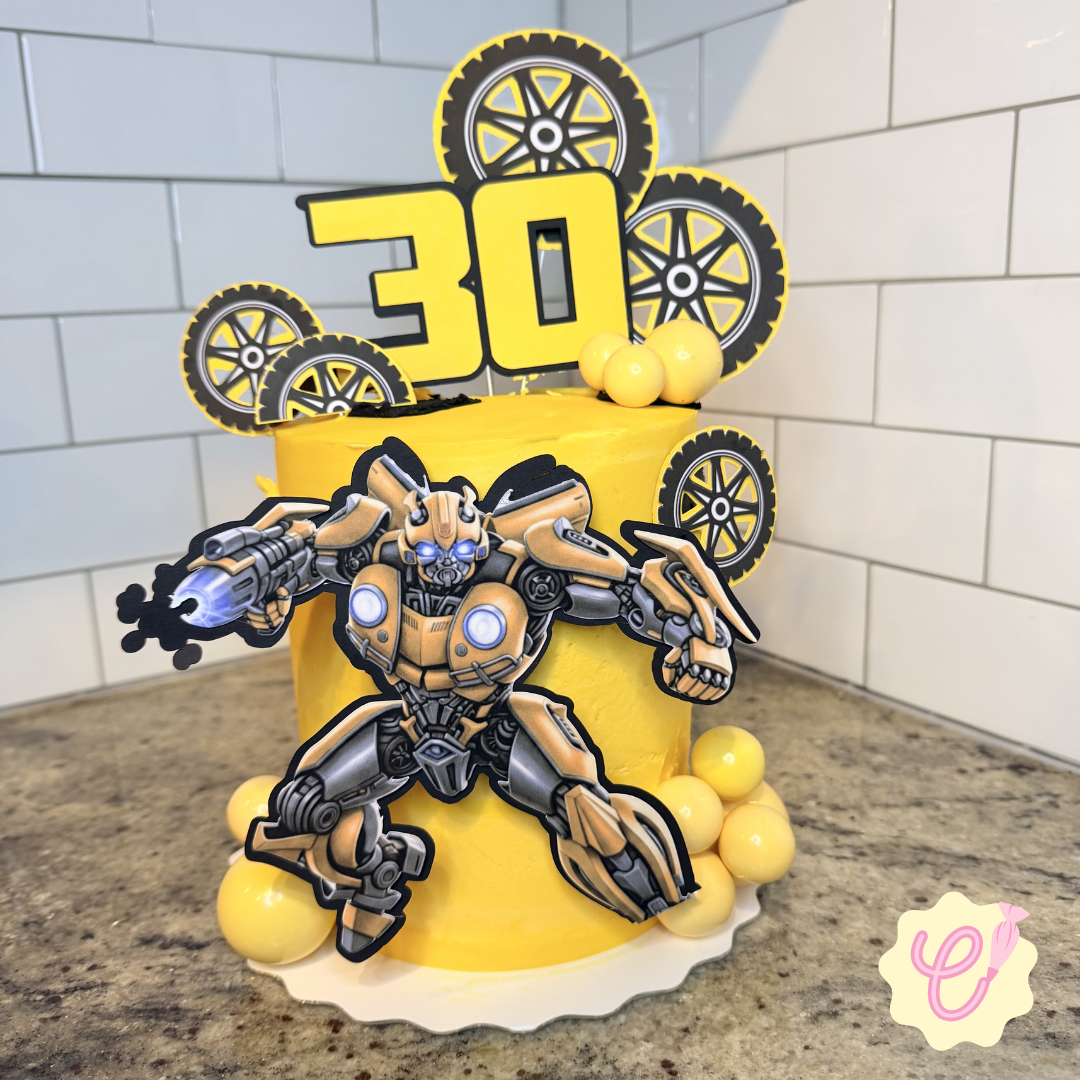 A two-tier yellow birthday cake decorated with a robot figure, yellow balls, and black and yellow gear toppers, celebrating a 30th birthday.