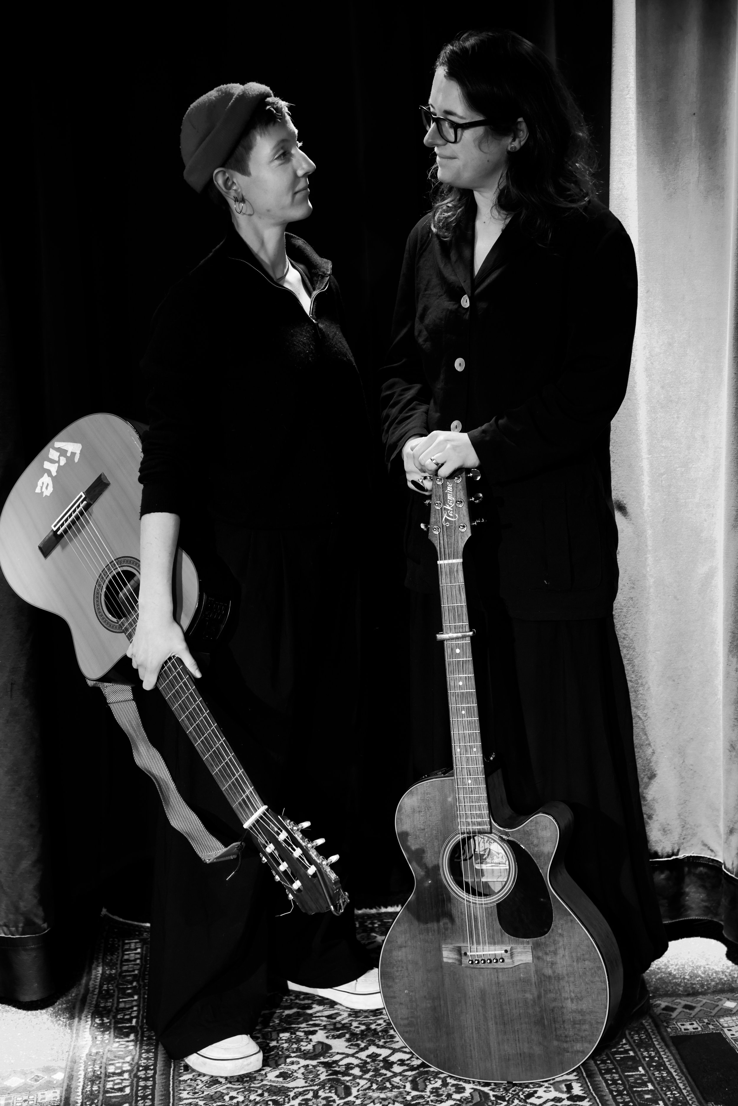 schwarz weiß Bild, HANNA&LIA stehend sich gegenüber und schauen sich an, halten die Gitarren in der Hand