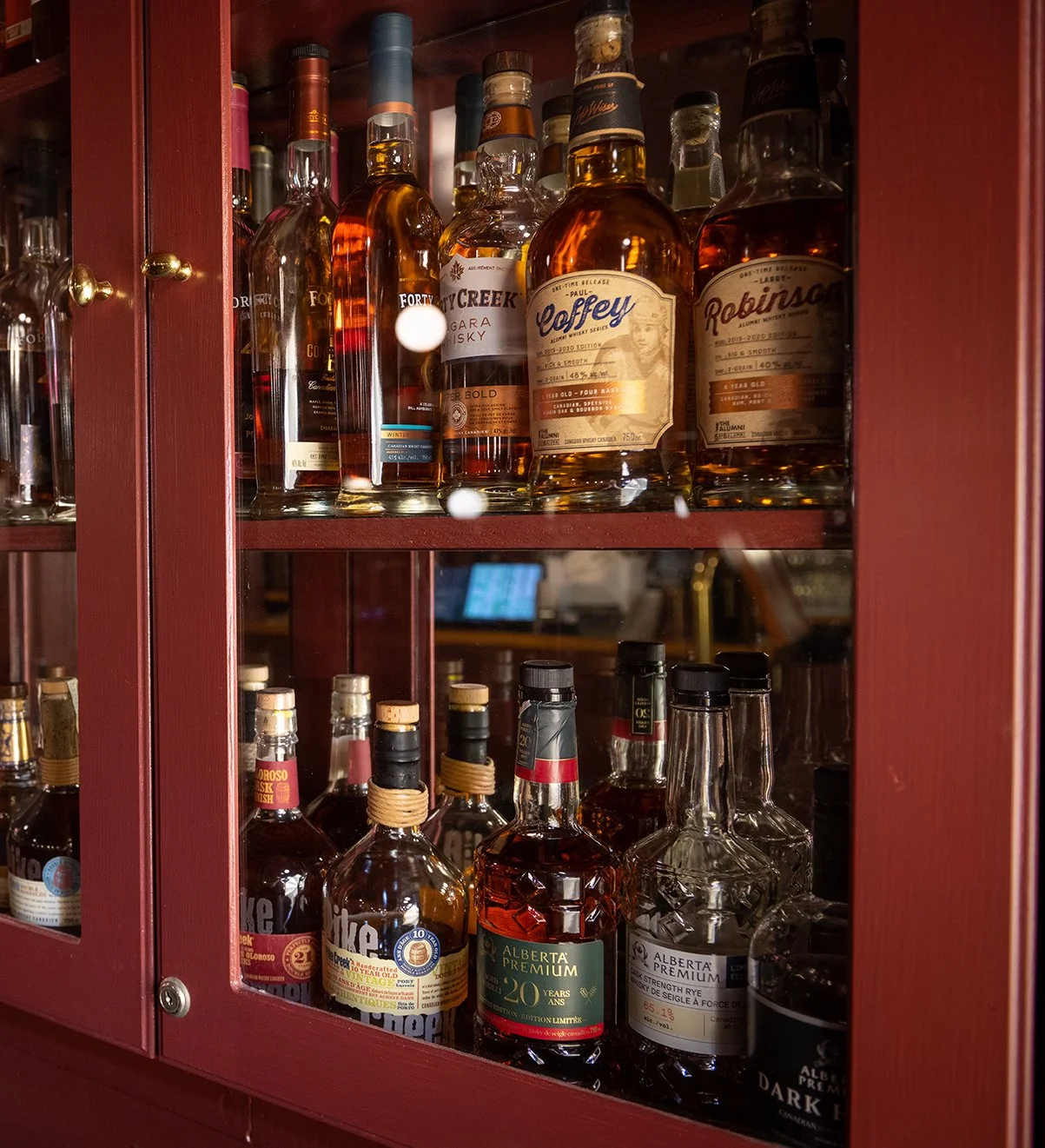 A glass cabinet filled with various bottles of whiskey and spirits.
