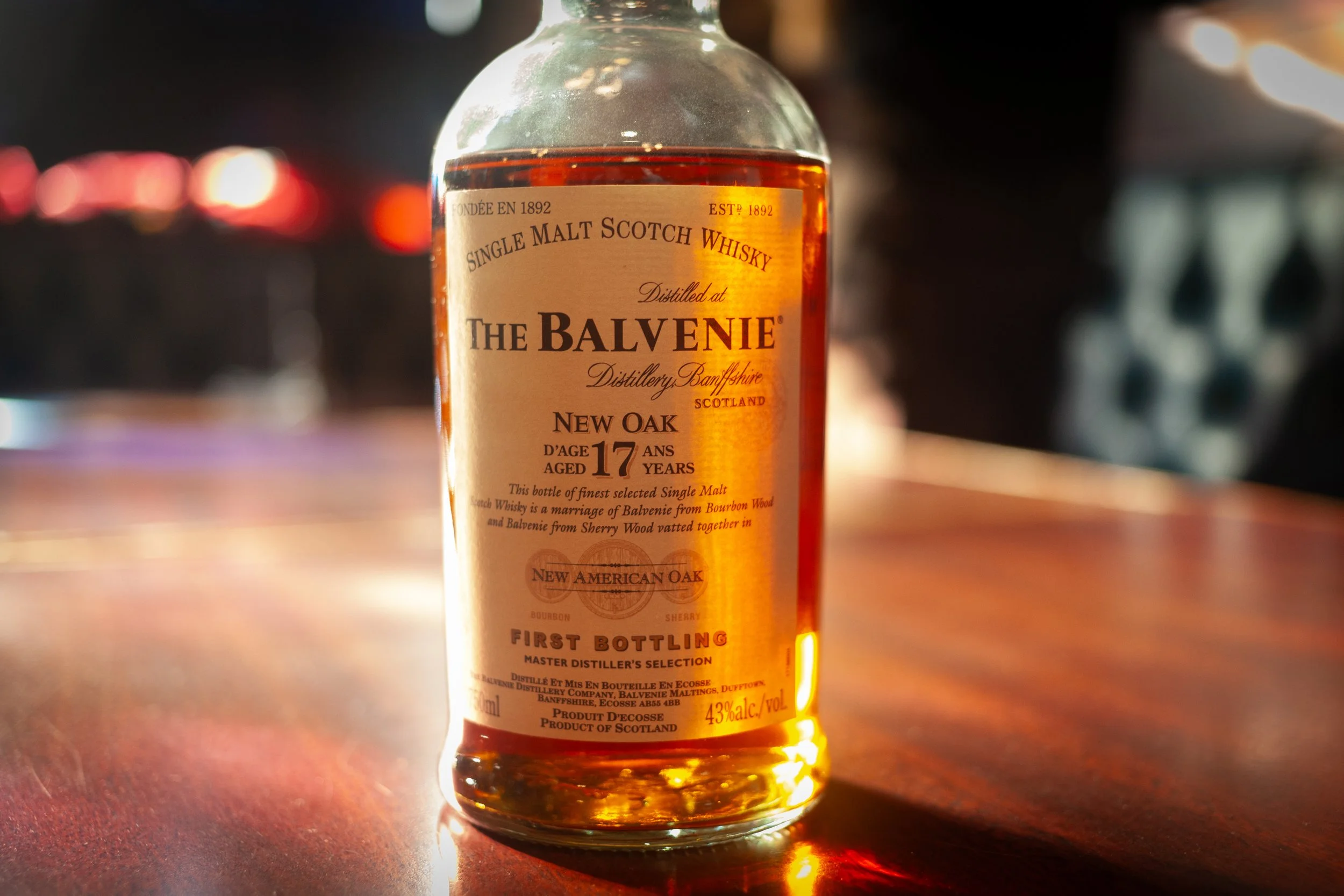 Bottle of The Balvenie single malt Scotch whisky on a wooden surface with a blurred background.