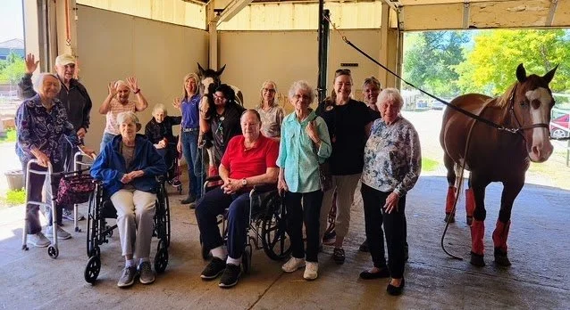 Group of elderly people and caregivers with a horse participating in a session at The Right Step Inc.
