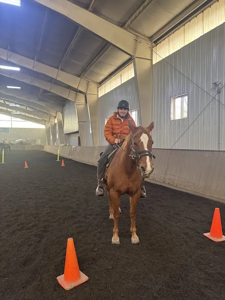Person riding a horse at The Right Step Inc. indoor riding arena with orange cones set up along the path.