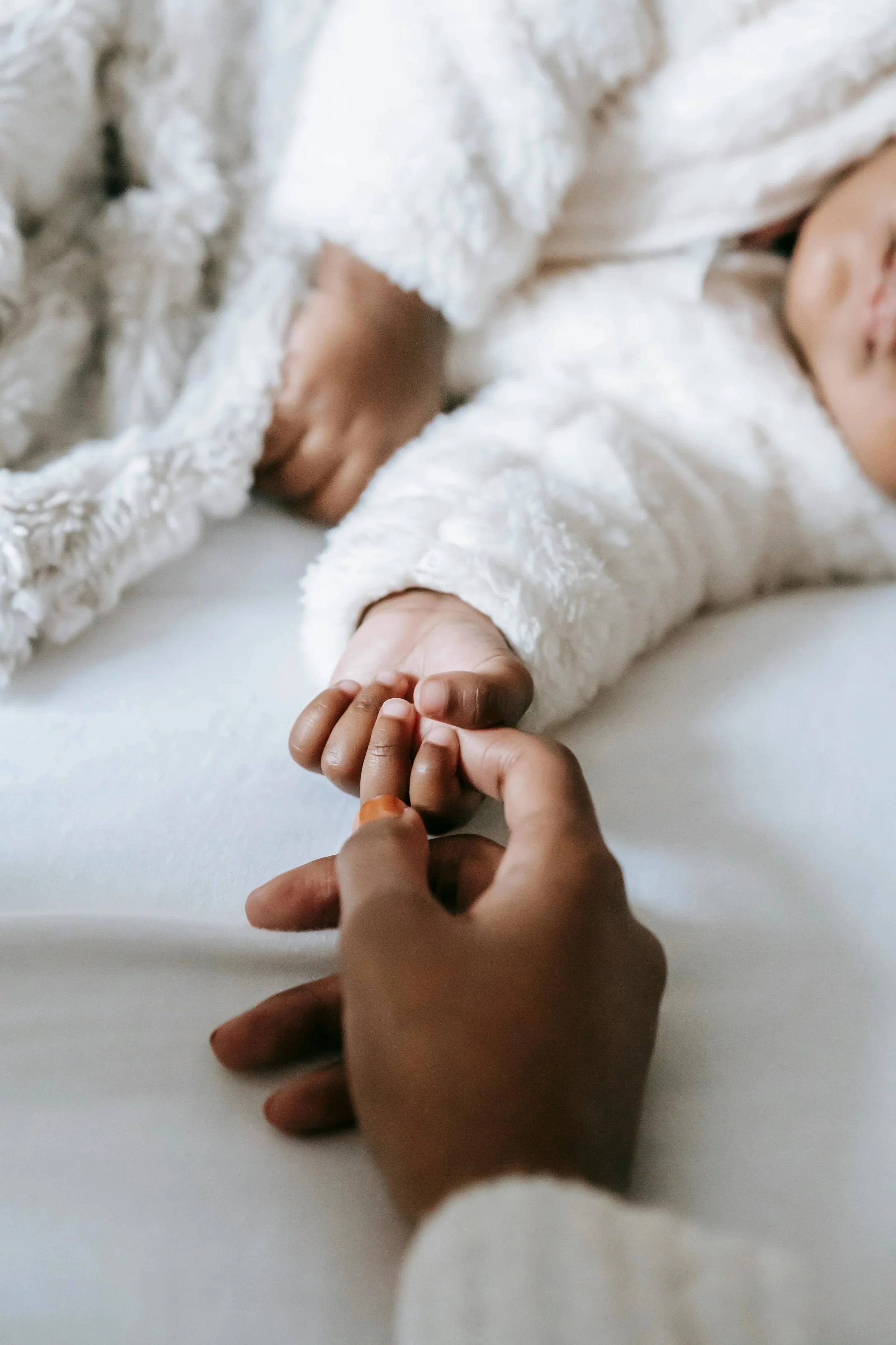 Mom and baby holding hands while baby is sleeping because Bloom her Path provides excellent pelvic floor therapy and infant feeding & lactation therapy in Corpus Christi, TX