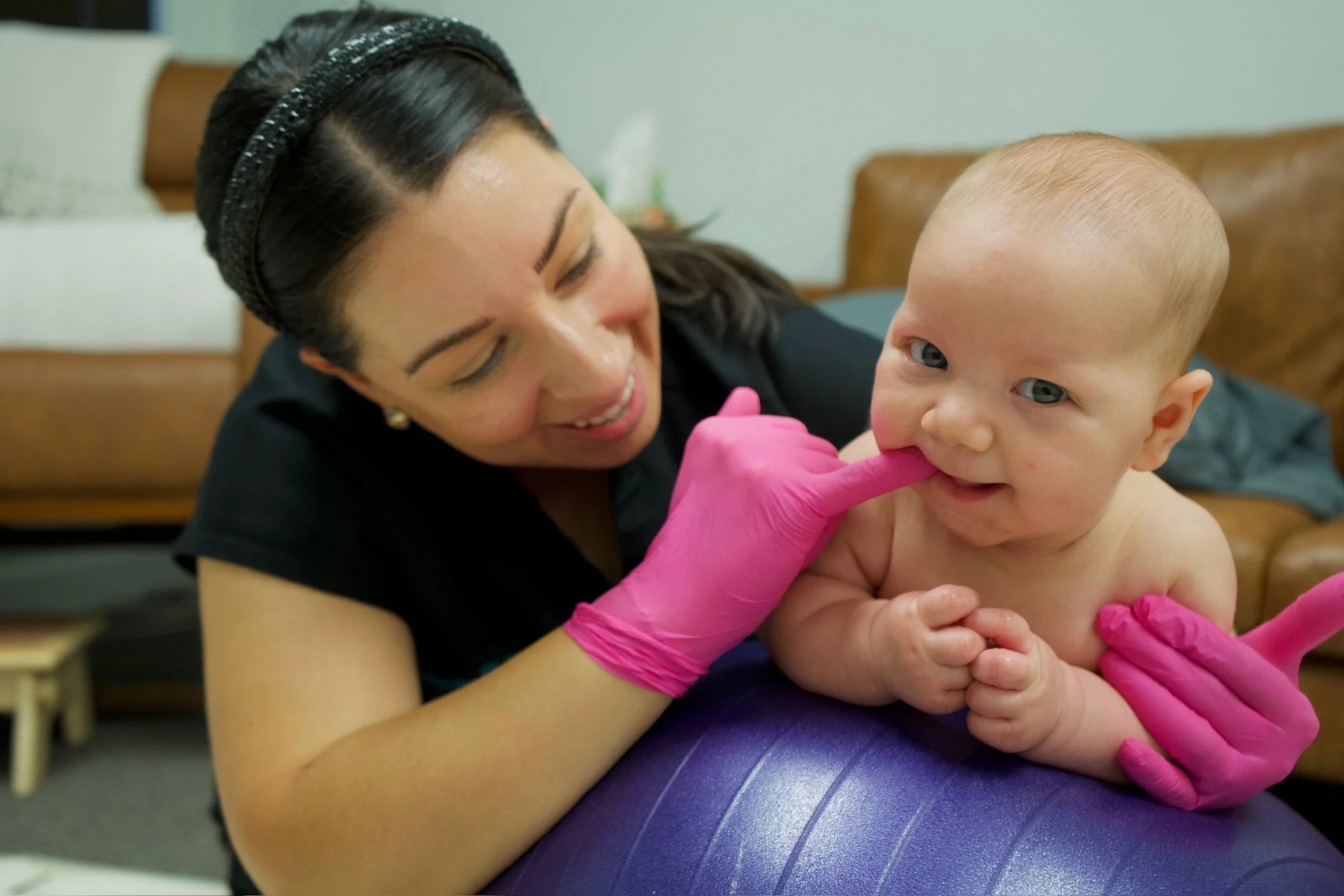 Haydee Medrano, co-owner and occupational therapist at Bloom Her Path, working with an infant pre-frenectomy with a lip and tongue tie on a peanut ball tummy time