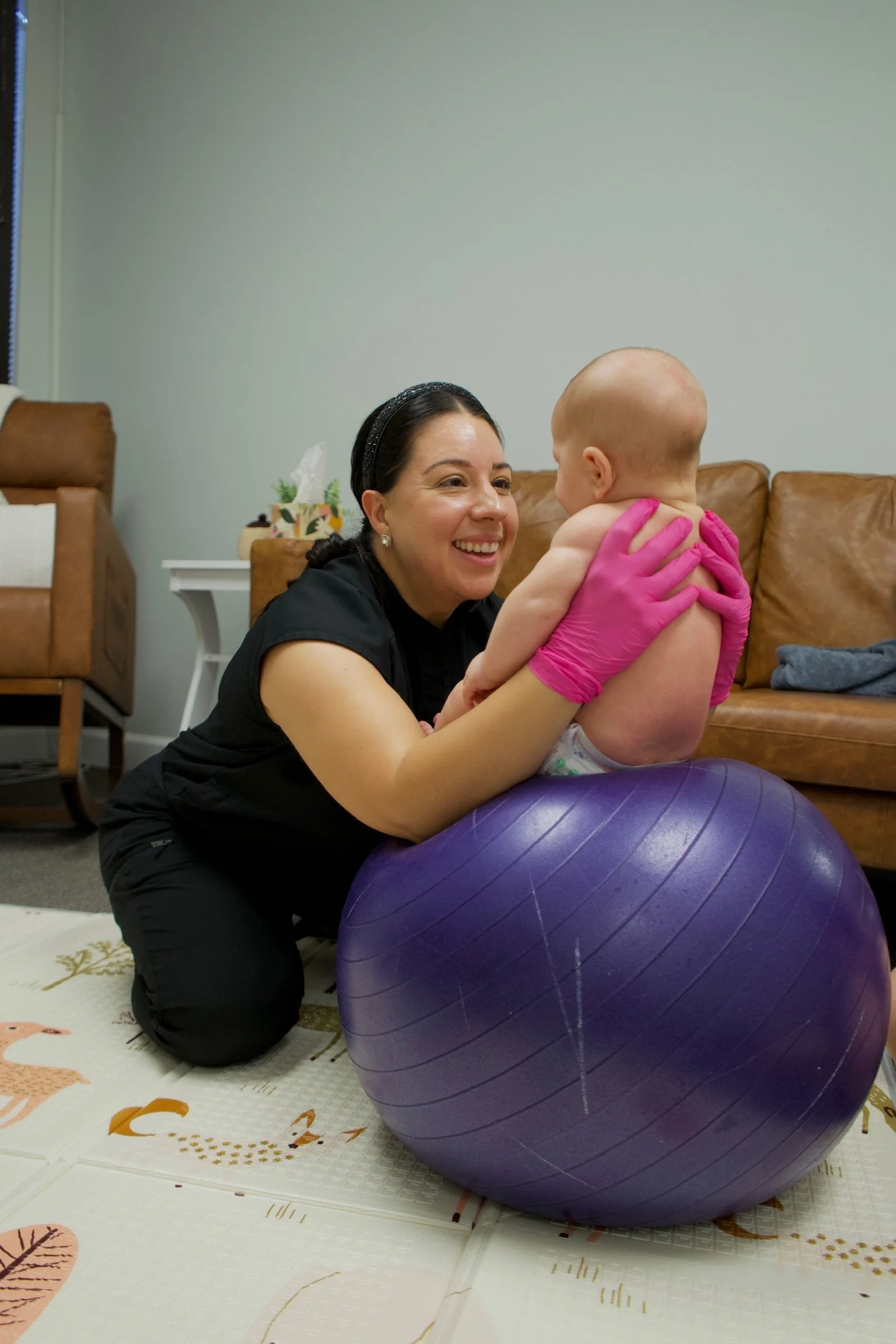 Haydee Medrano plays with a baby on a therapy ball while treating body tension, torticollis, oral motor skills, and core strength