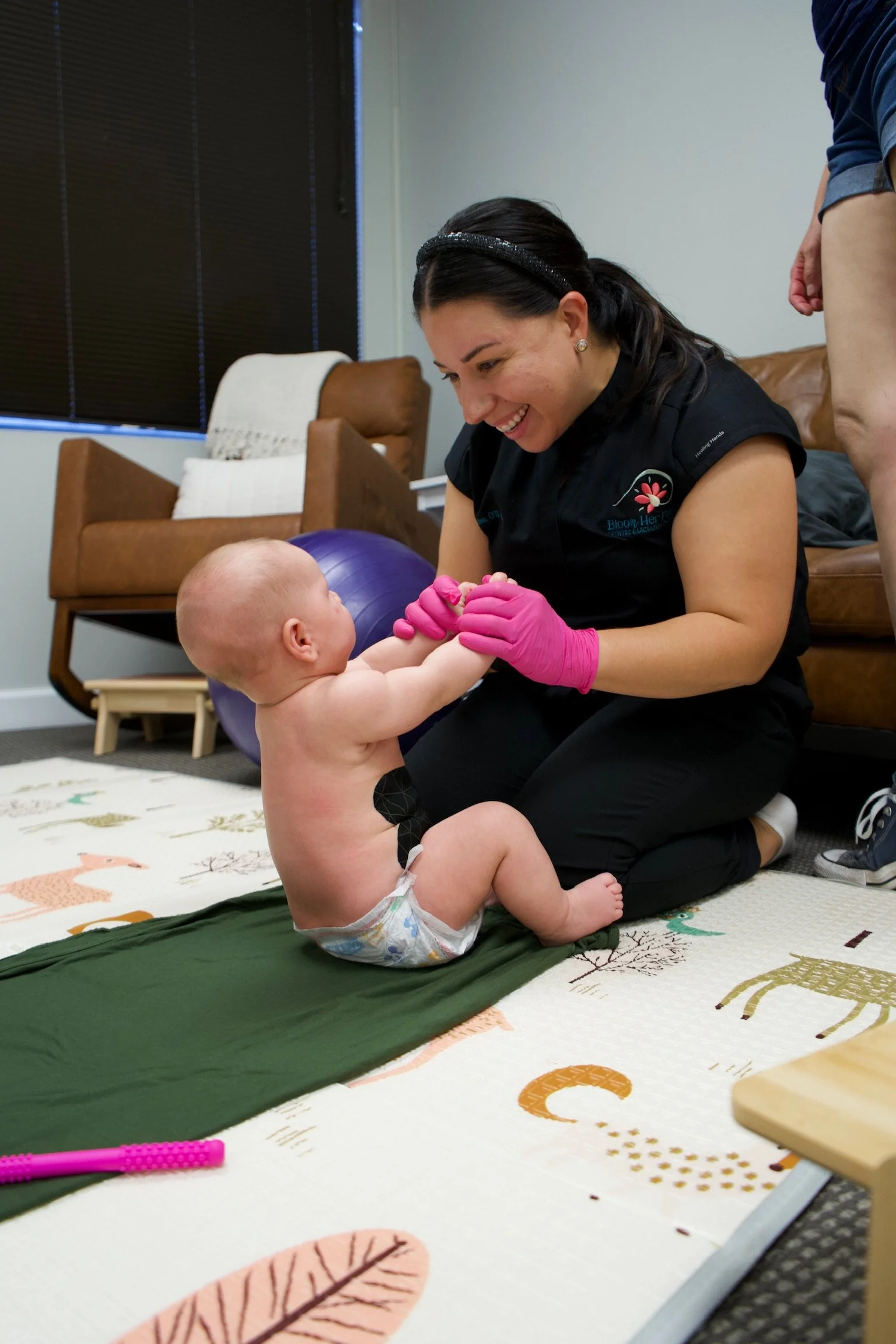 Haydee Medrano, occupational therapist and co-owner of Bloom Her Path in Corpus Christi, TX plays with an infant on the floor to provide therapy for body tension, torticollis, head-turn preference, head tilt, arching and stiff movements