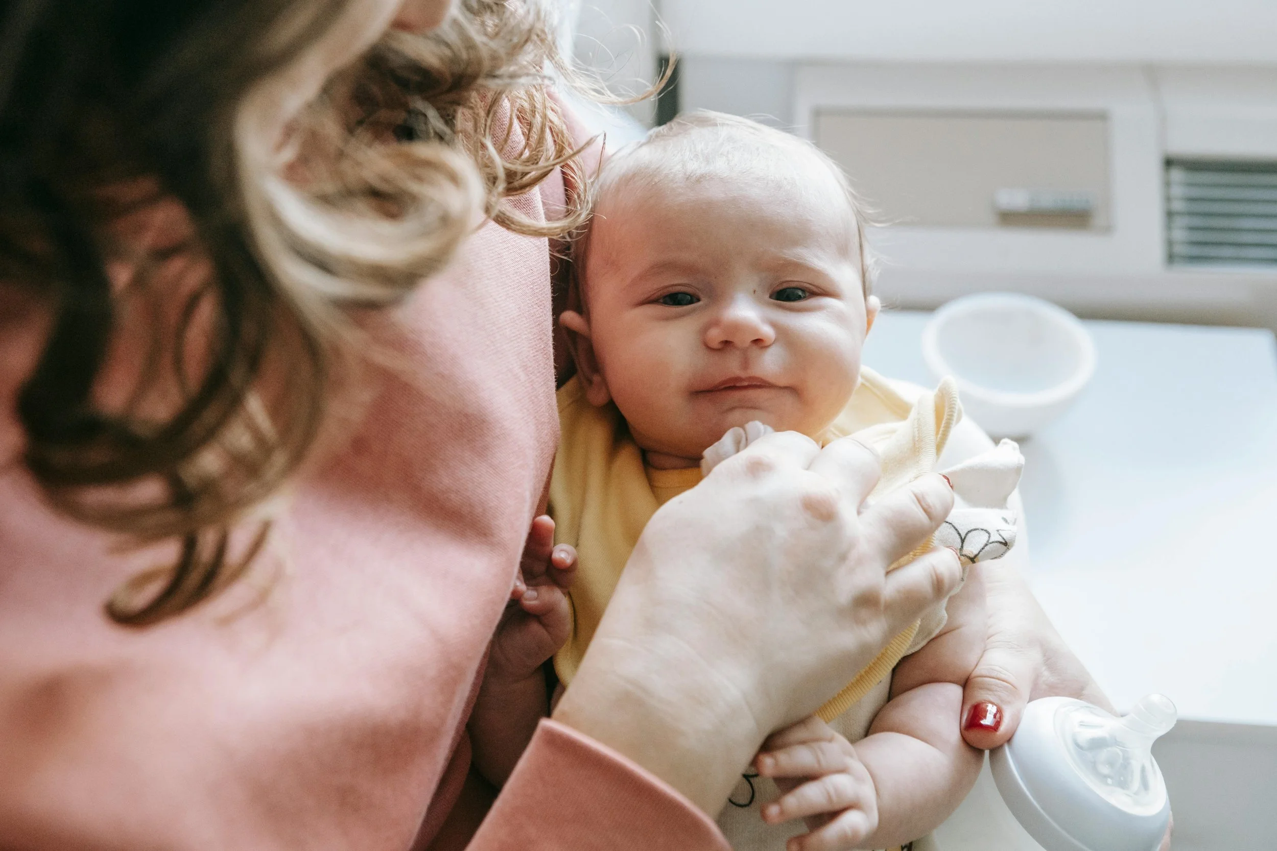 Newborn baby with a bottle held by mom because Bloom Her Path provides you with professional and product resources to guide you through postpartum