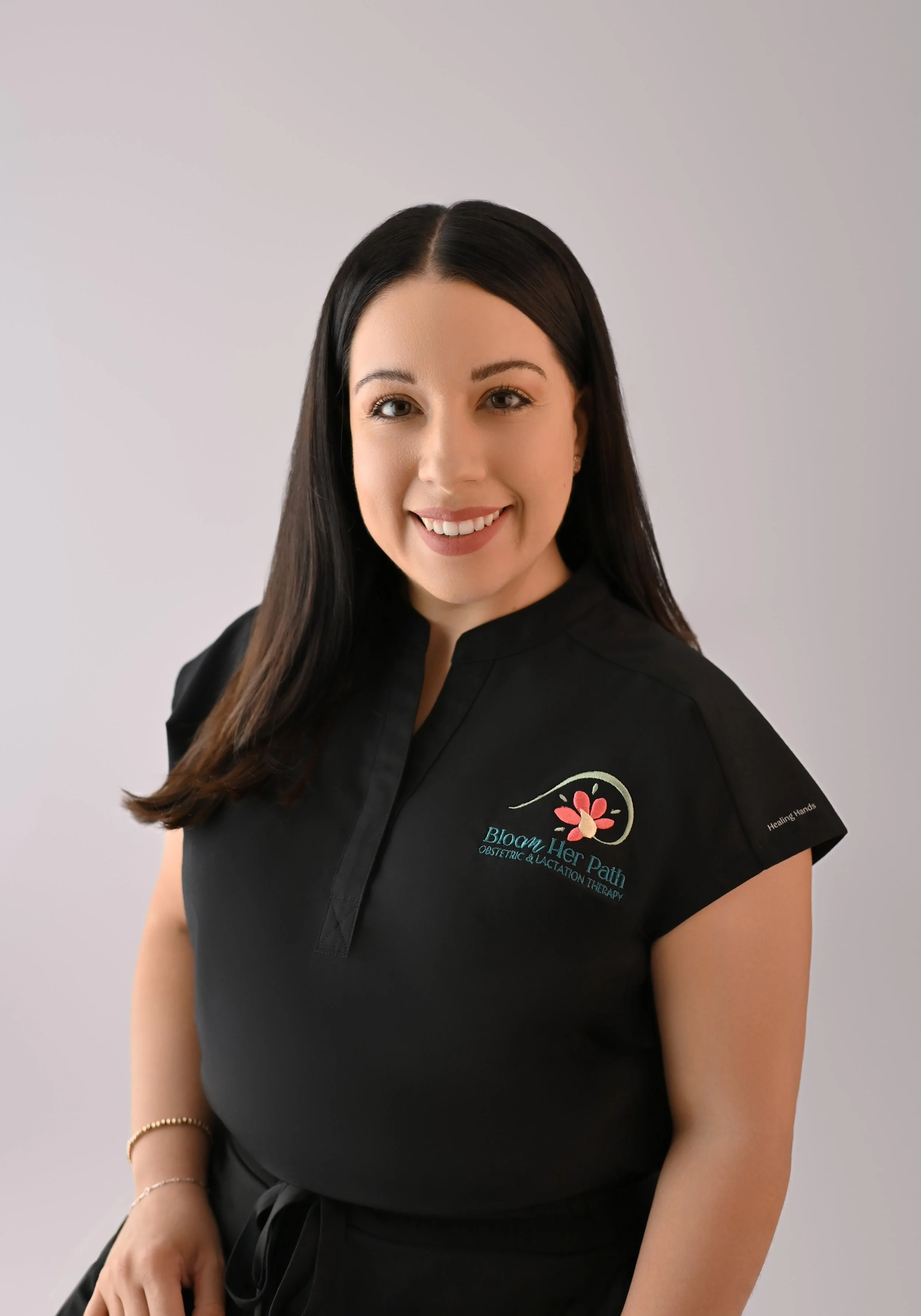 Haydee Medrano headshot with her dark hair down and black scrubs on. She is a co-owner of Bloom Her Path in Corpus Christi, TX