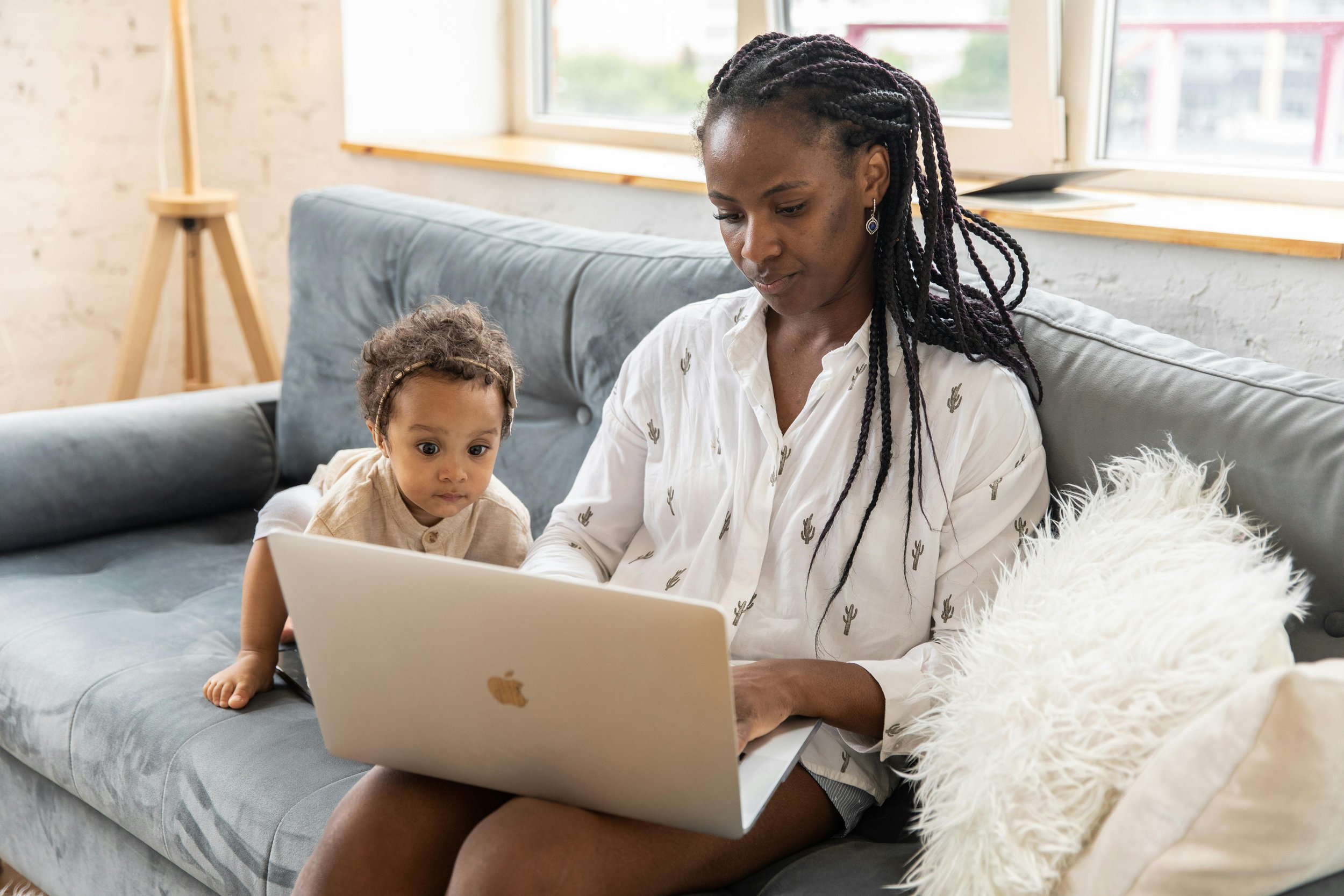 Mom on a computer and toddler sitting next to her reading the blog for Bloom Her Path