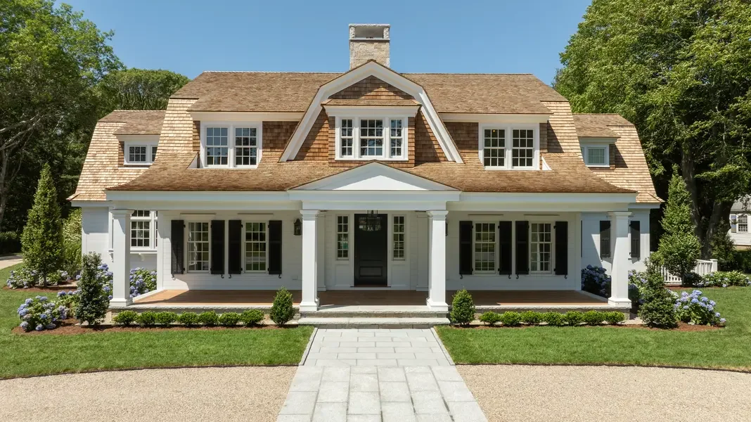 This image presents a stunning example of classic New England architecture featuring a beautifully restored Cape Cod-style home. The residence showcases the perfect blend of traditional design elements with contemporary refinements.
The home's most