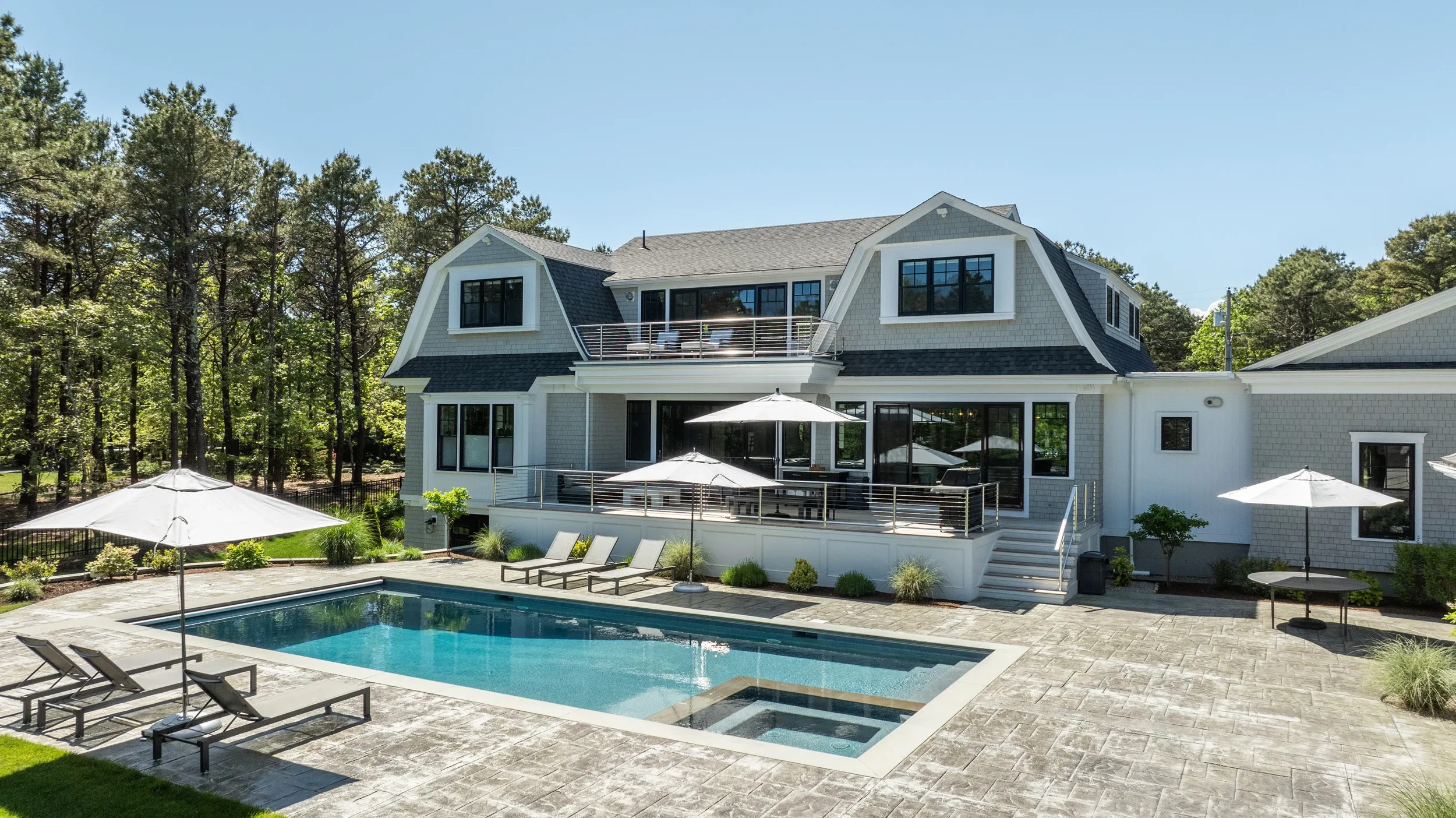 Modern house with multiple decks and a backyard swimming pool with lounge chairs and umbrellas