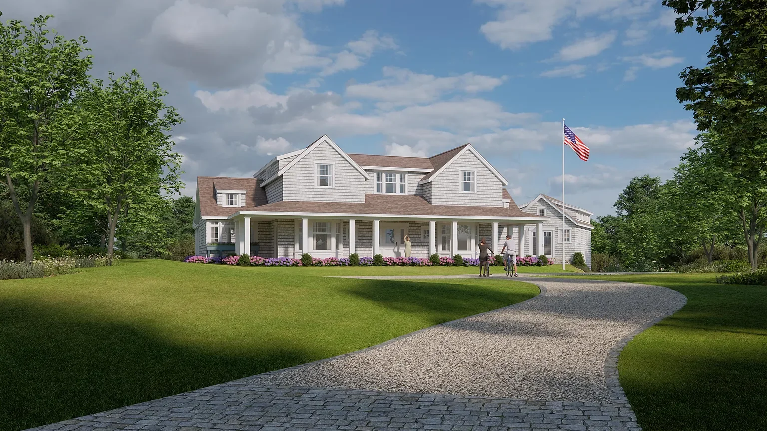 A large white house with a wraparound porch in a green yard with trees and a gravel pathway. There are three people on bikes near the porch and an American flag on a pole.