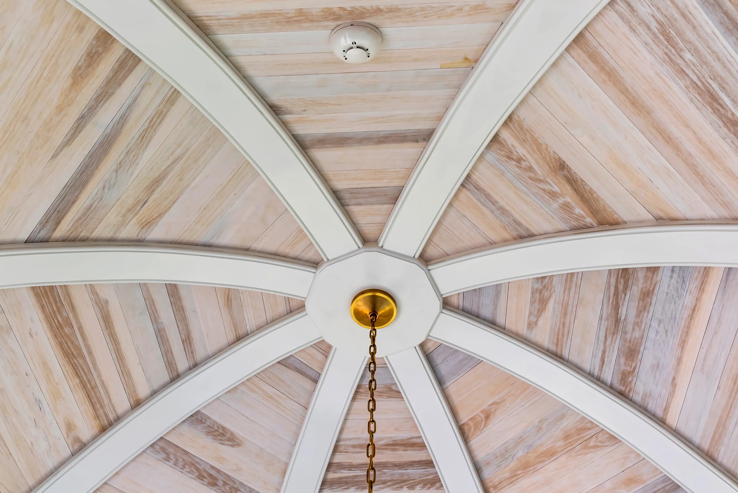 Ceiling with wooden panels and a central circular fixture with a hanging chain.