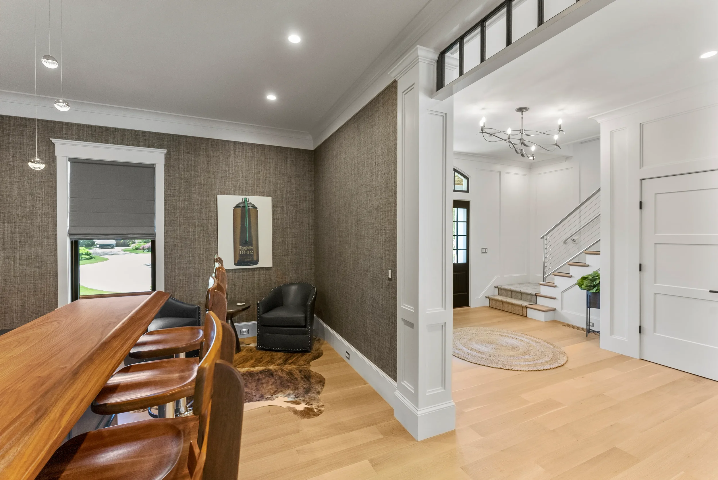 Interior view of a modern home with a dining area on the left and a foyer with stairs on the right.