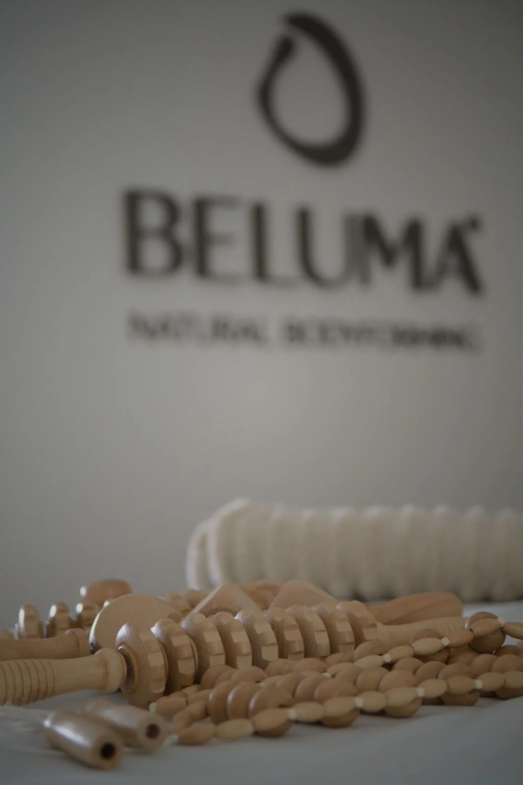 Wooden hairbrushes and a white towel or cloth in front of a blurred background with the BELUMA logo.