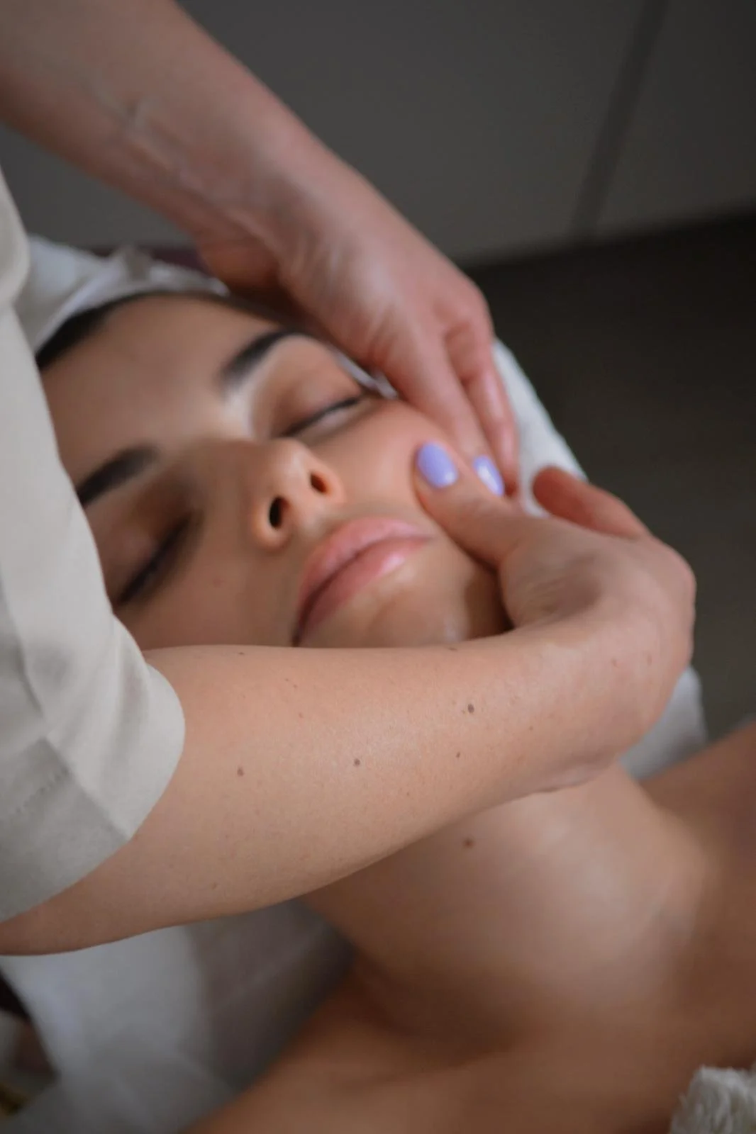 A woman receiving a facial massage in a spa setting.