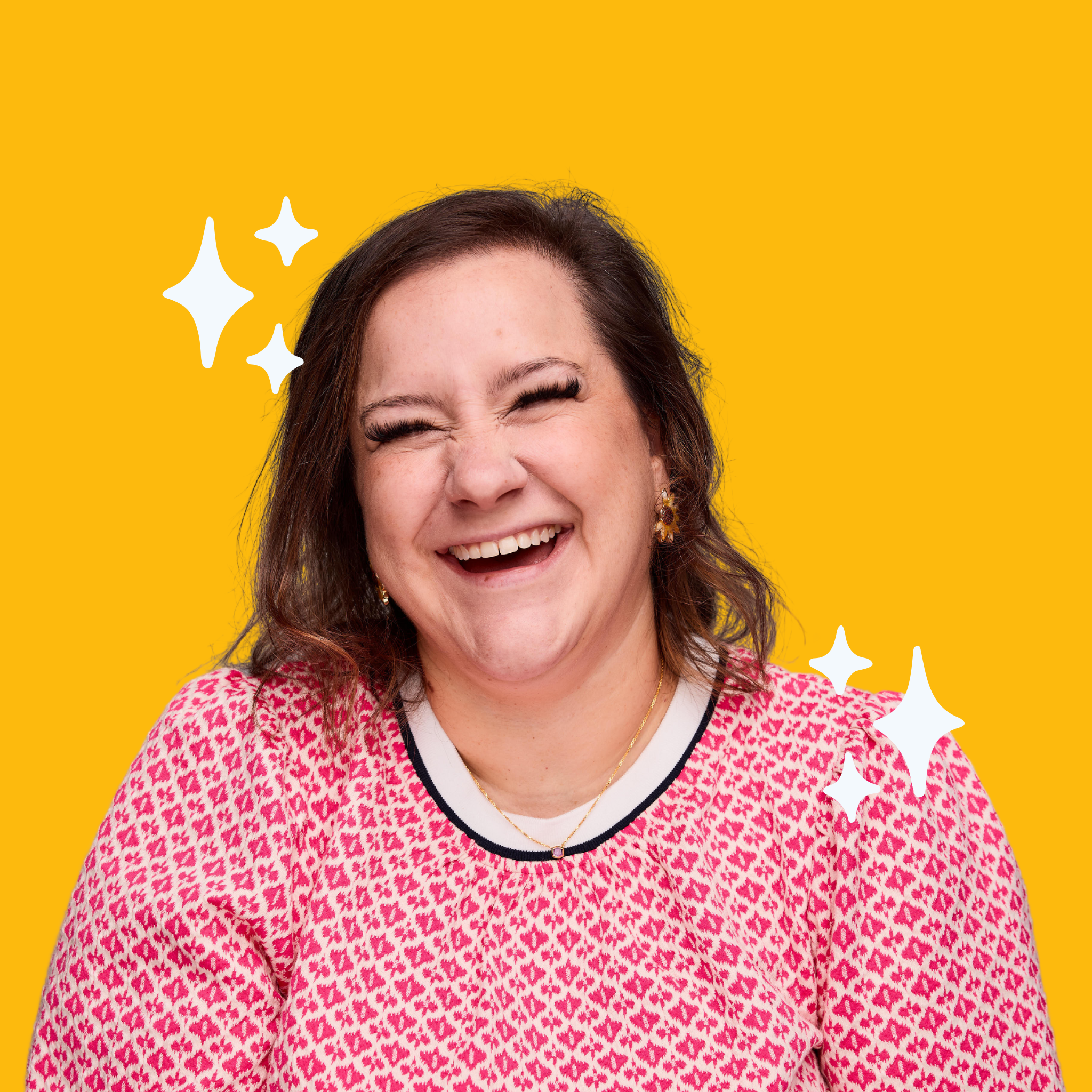 A woman with shoulder-length brown hair smiling and laughing, wearing a pink patterned top with a white collar, against a bright yellow background with white sparkles.