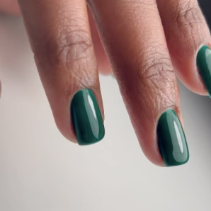 Close-up of a hand with dark green painted nails.