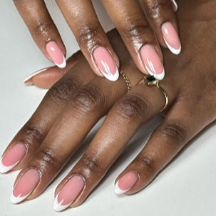 Close-up of well-manicured hands with pink and white French nails, adorned with rings.