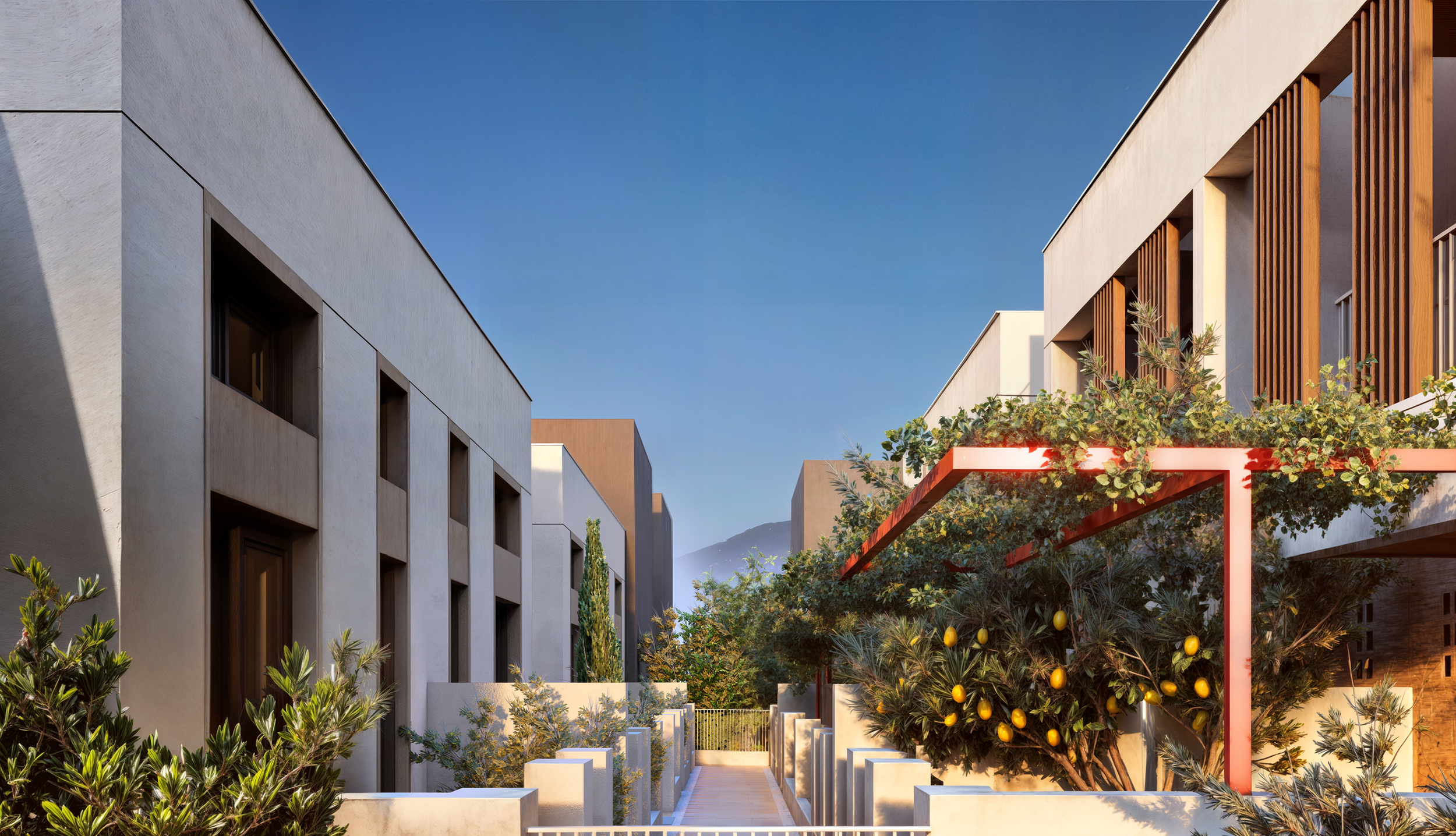 Modern residential buildings with a pathway, greenery, and a blue sky.