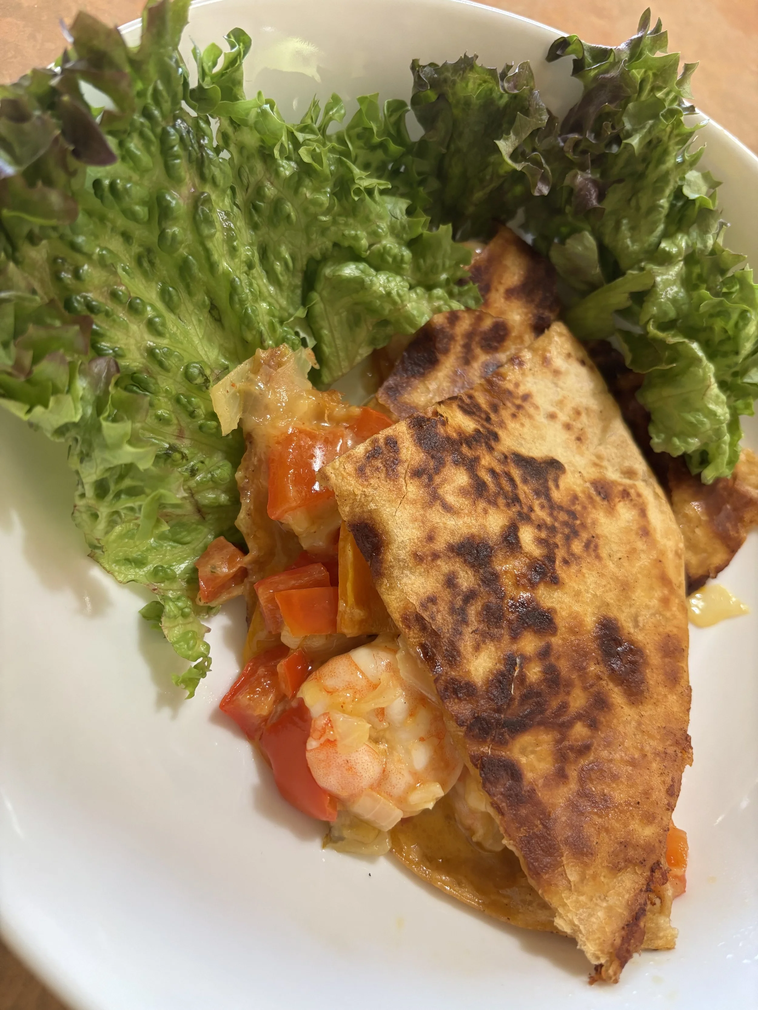 A plate with a stuffed pastry, fresh green lettuce, and a side of mixed vegetables.