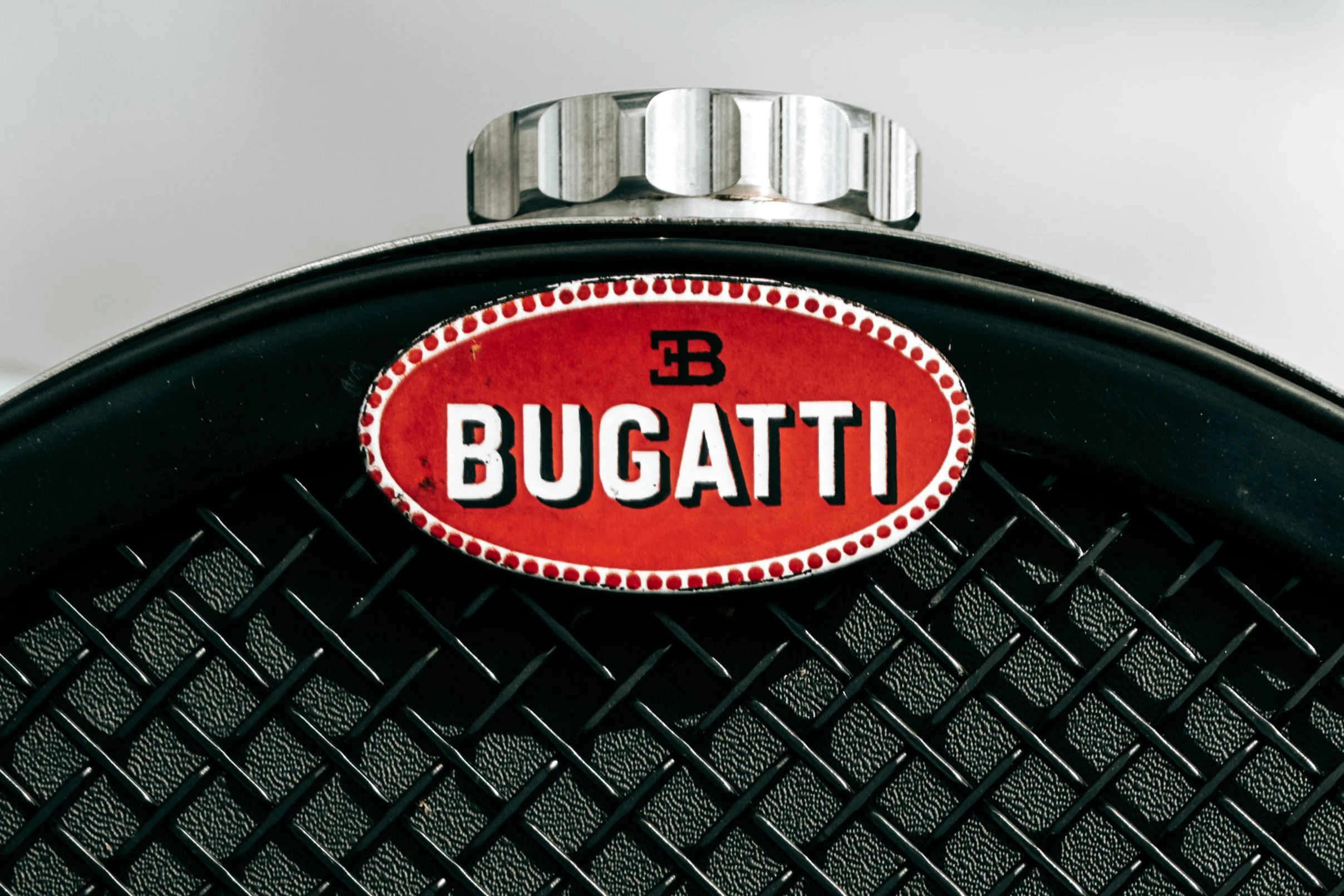 Close-up of a black metal fan with a red and white Bugatti logo in the center.