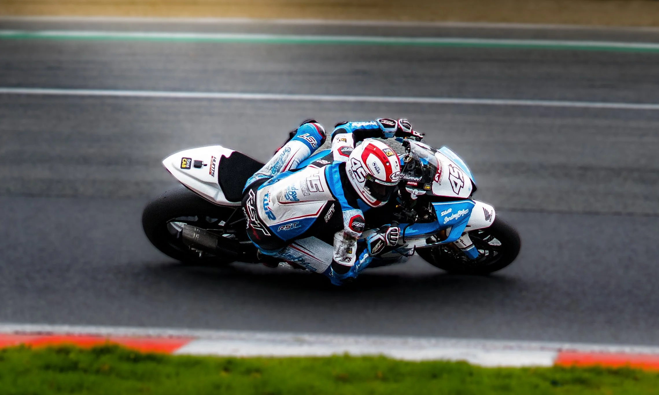 A professional motorcycle racer in full racing gear leaning into a turn on a race track.