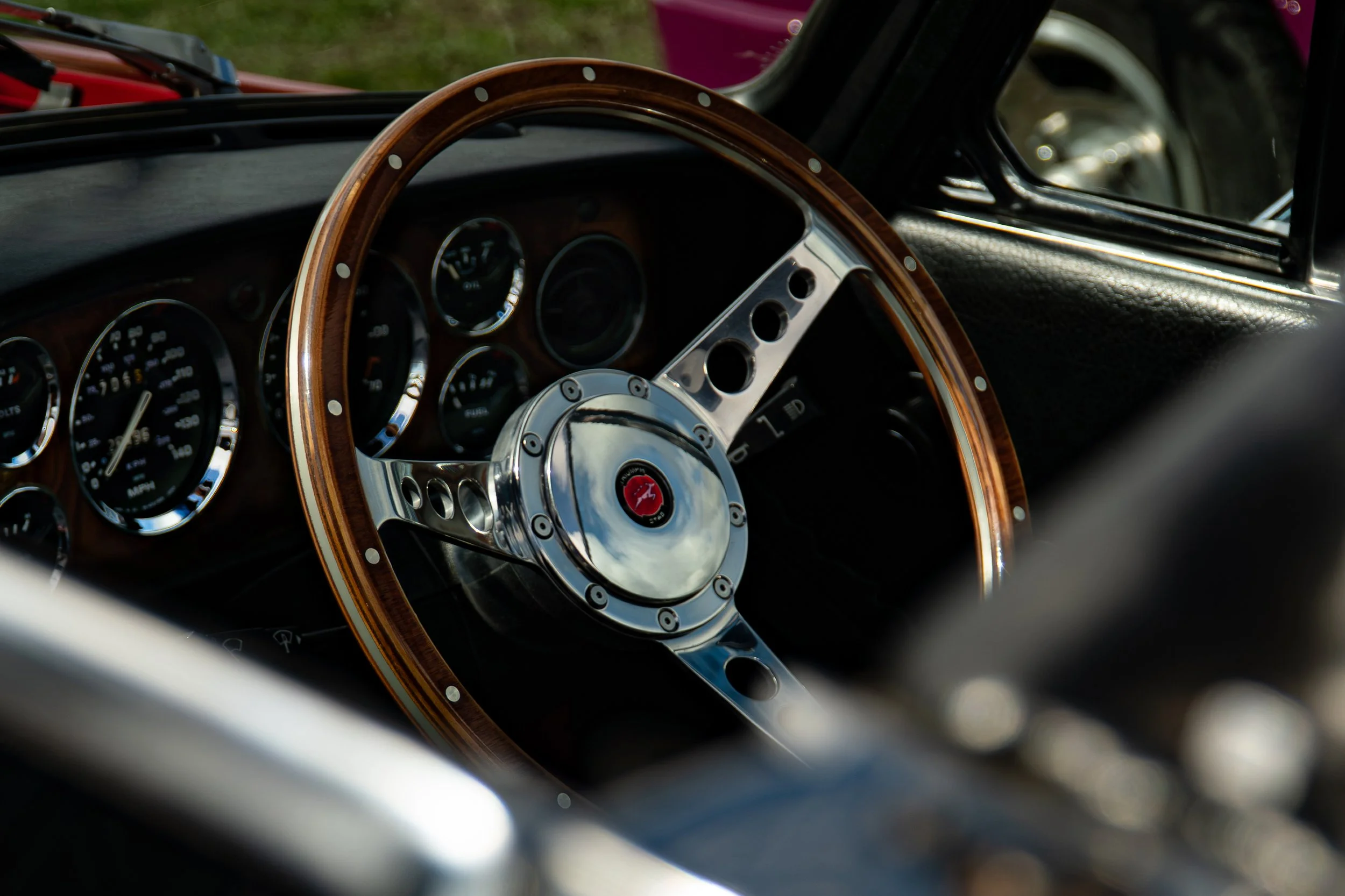 Close-up of a vintage car's interior dashboard and steering wheel with a wood finish.