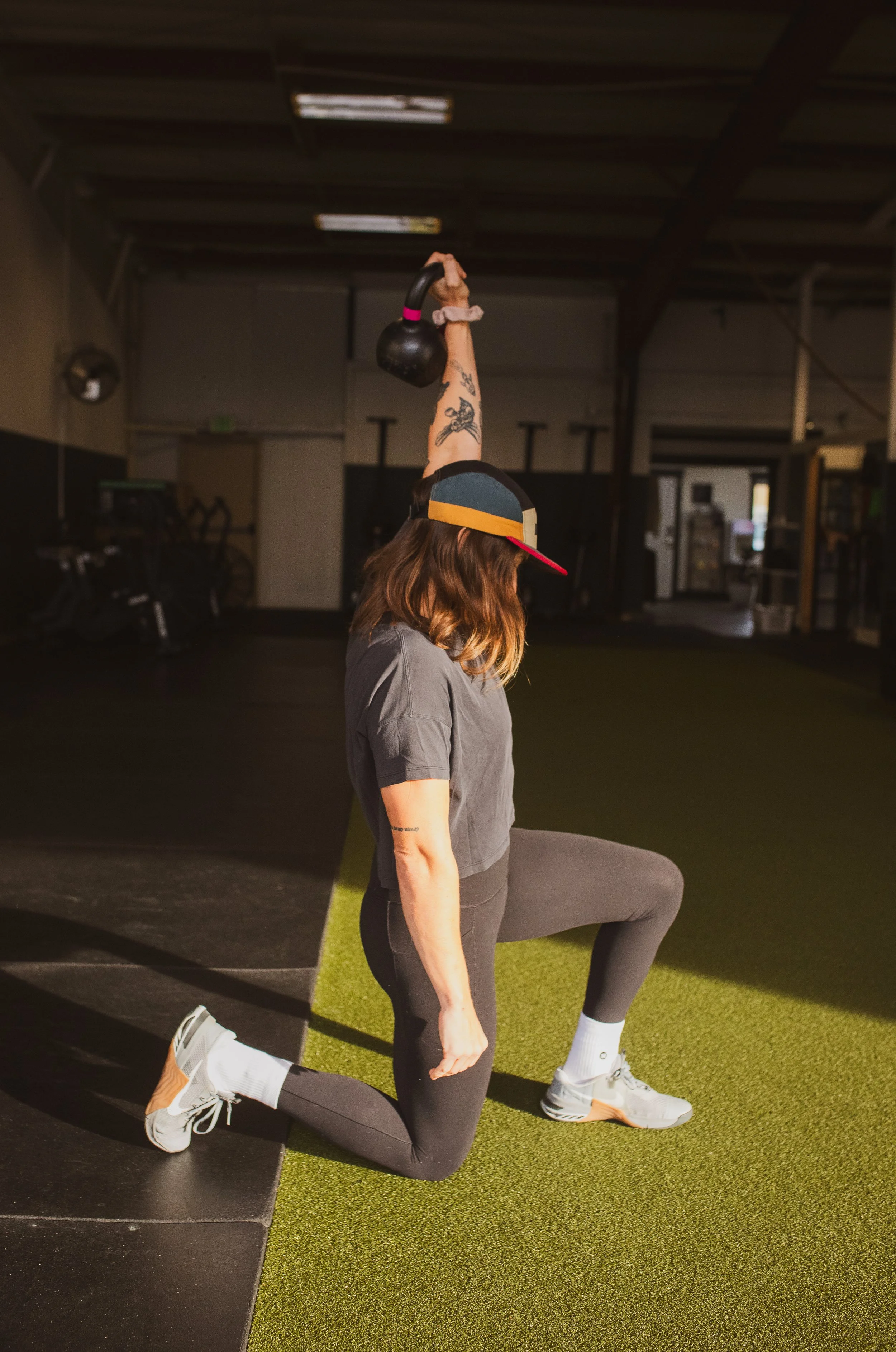 Woman in athletic wear performing a kettlebell exercise in a gym.