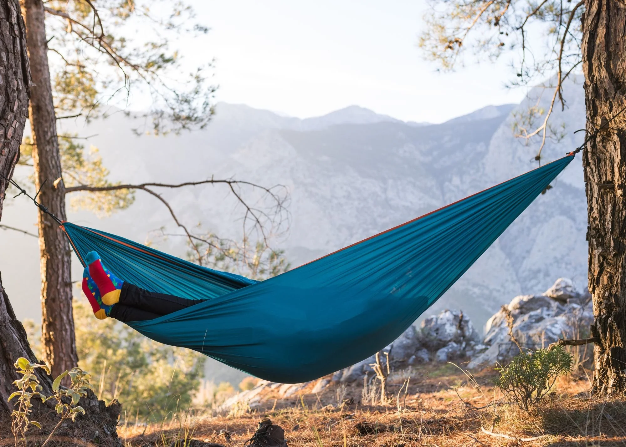 person laying in hammock in mountains