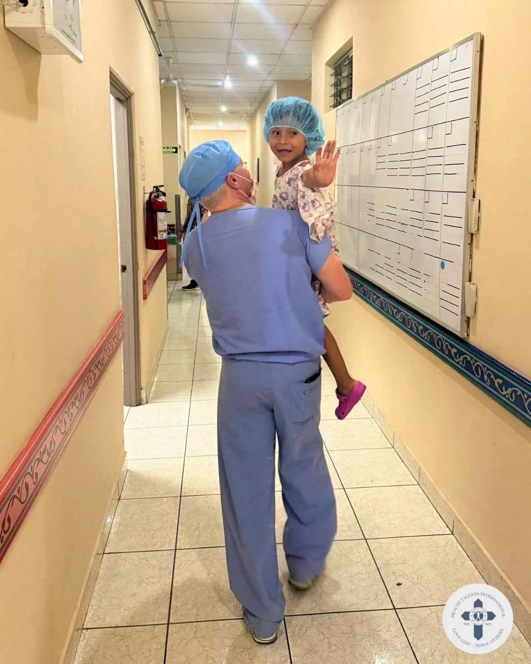 A brave little wave goodbye. 💛

In this moment, a volunteer carries a child off to surgery while a tiny hand waves with courage and trust. What could feel overwhelming is met with comfort, gentleness, and the steady presence of someone willing to wa