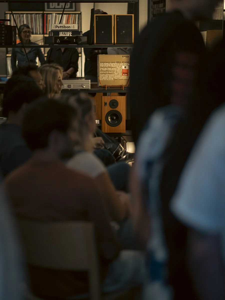 Silhouettes of people at sunset, some with arms raised, in an outdoor gathering.