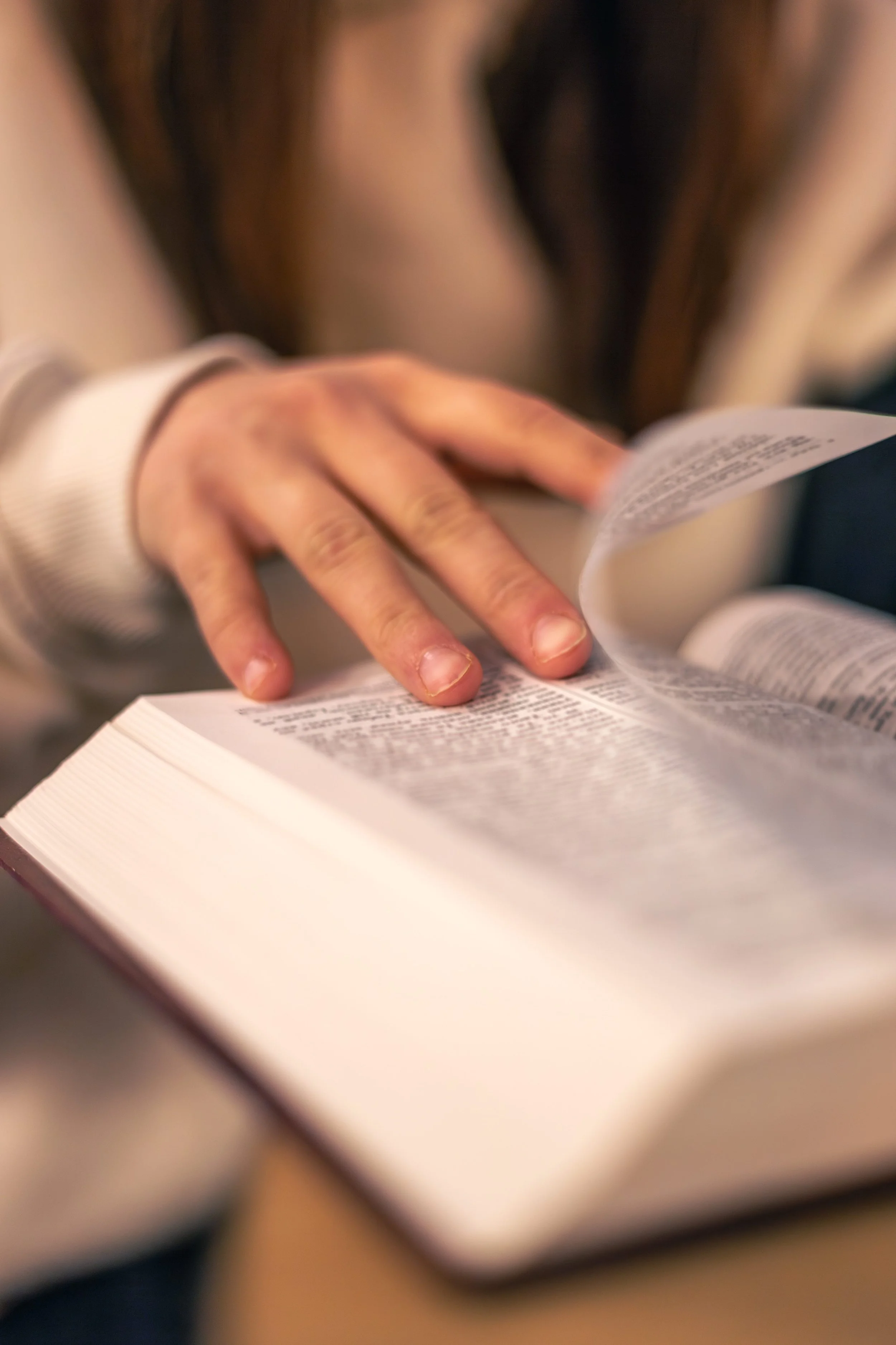 Close-up of a person's hand flipping through pages of a book or magazine.