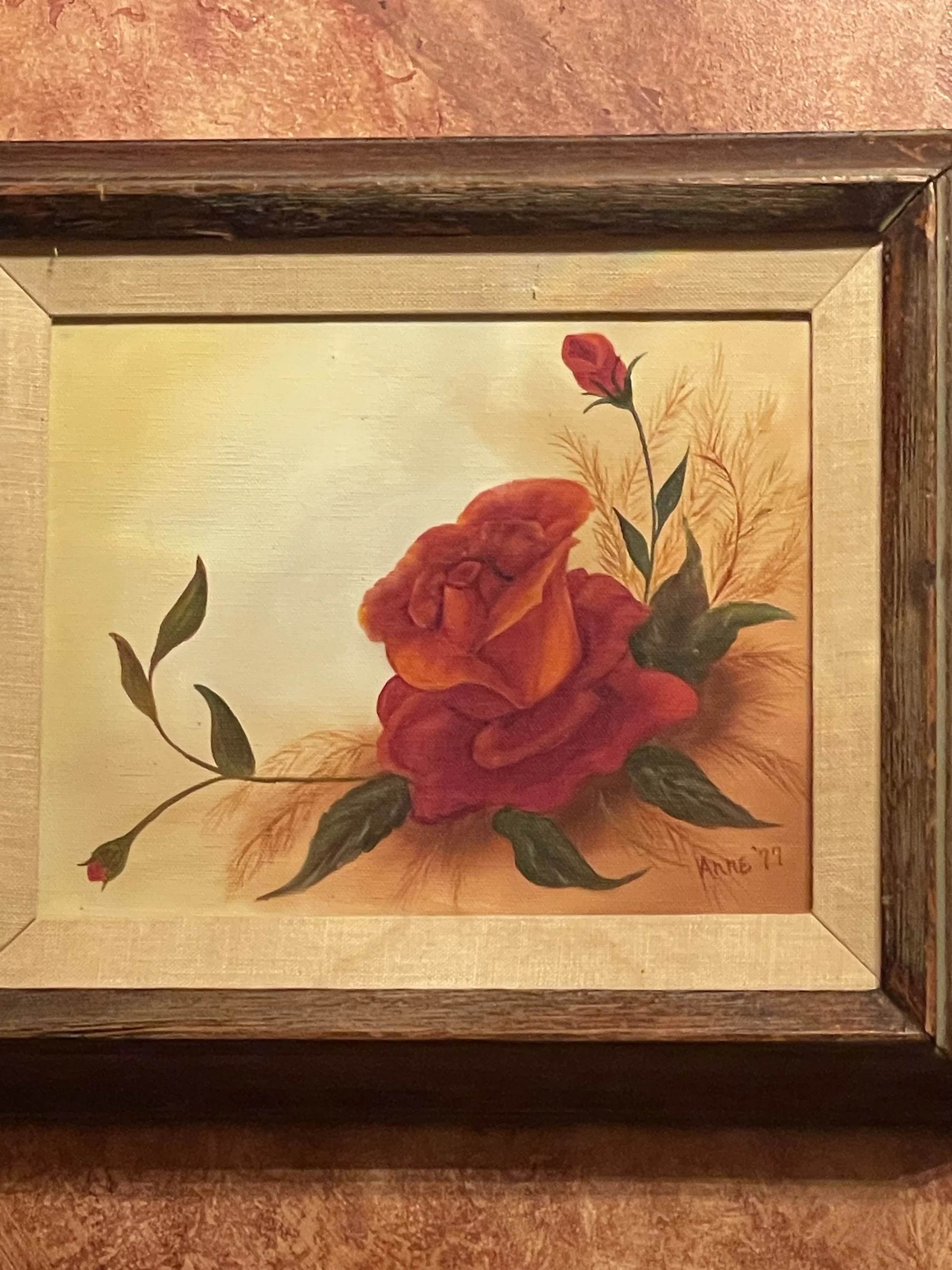 Painting of a red and orange rose with green leaves, signed 'Anne '77' in the bottom right corner.