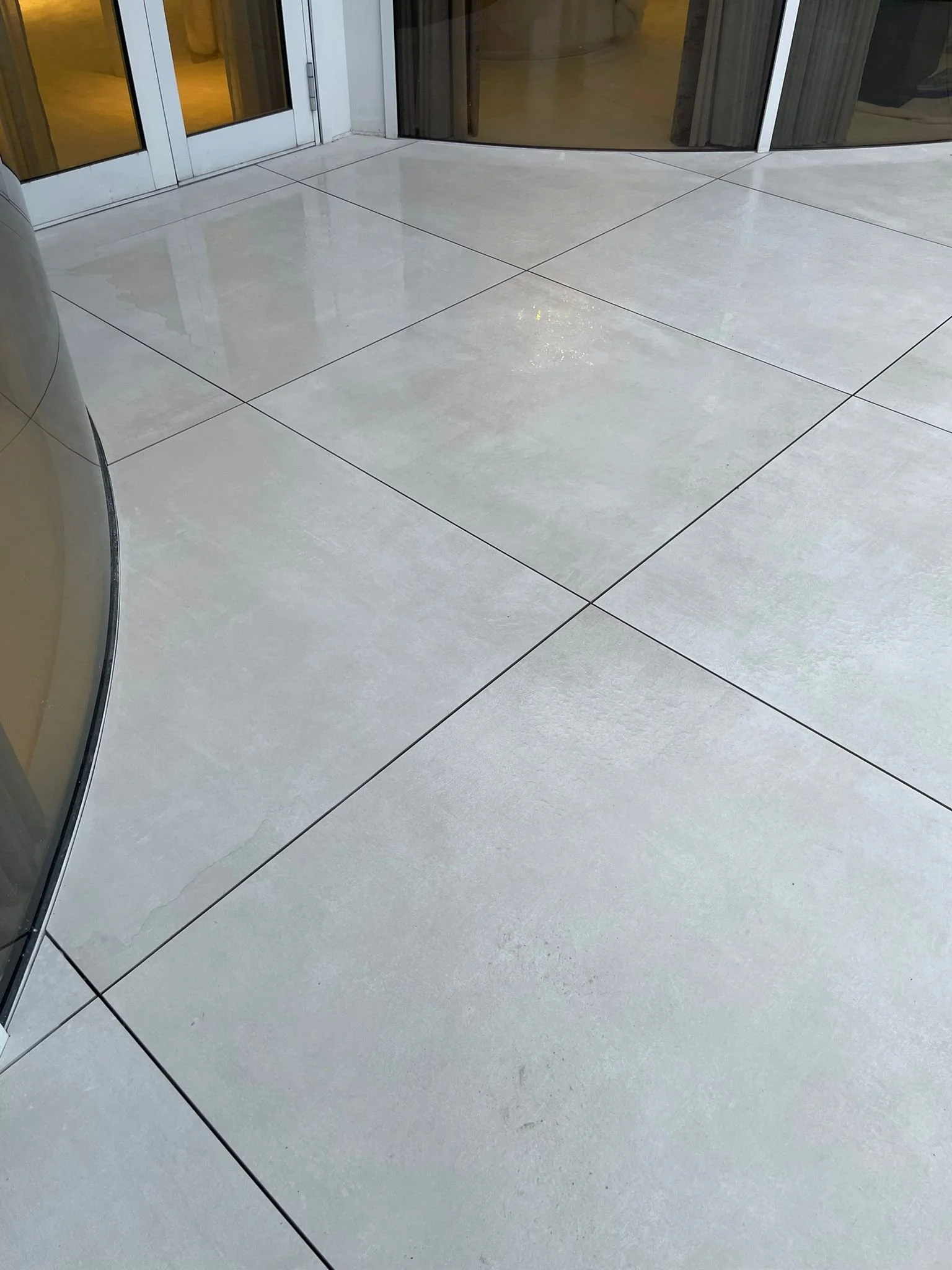 Clean beige tiled floor near glass doors.