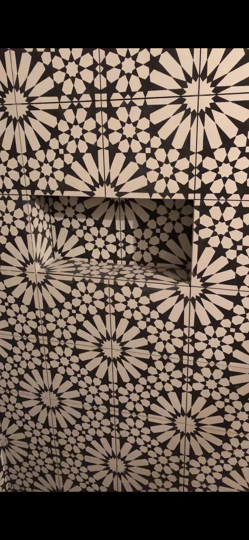 Black and white patterned wall with a built-in tiled shelf.