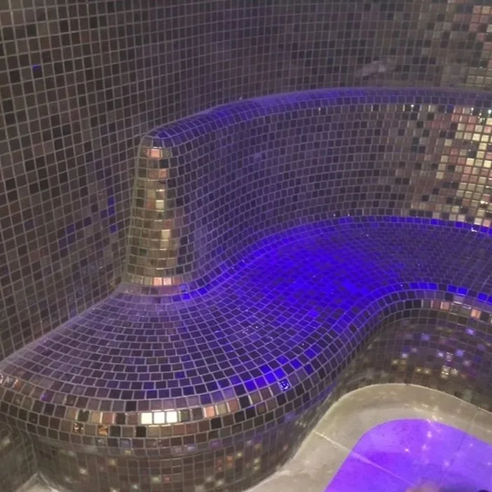 A mosaic-tiled seating area with purple lighting in a spa or sauna setting.