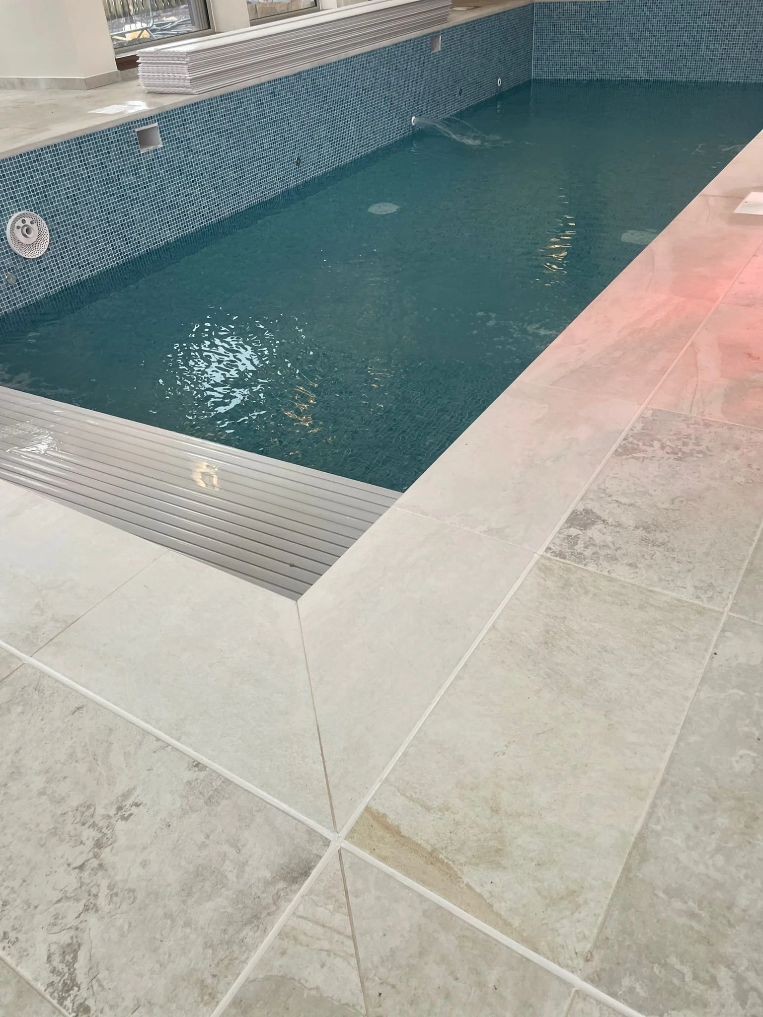 Indoor swimming pool with blue tiled walls and a beige tiled floor.
