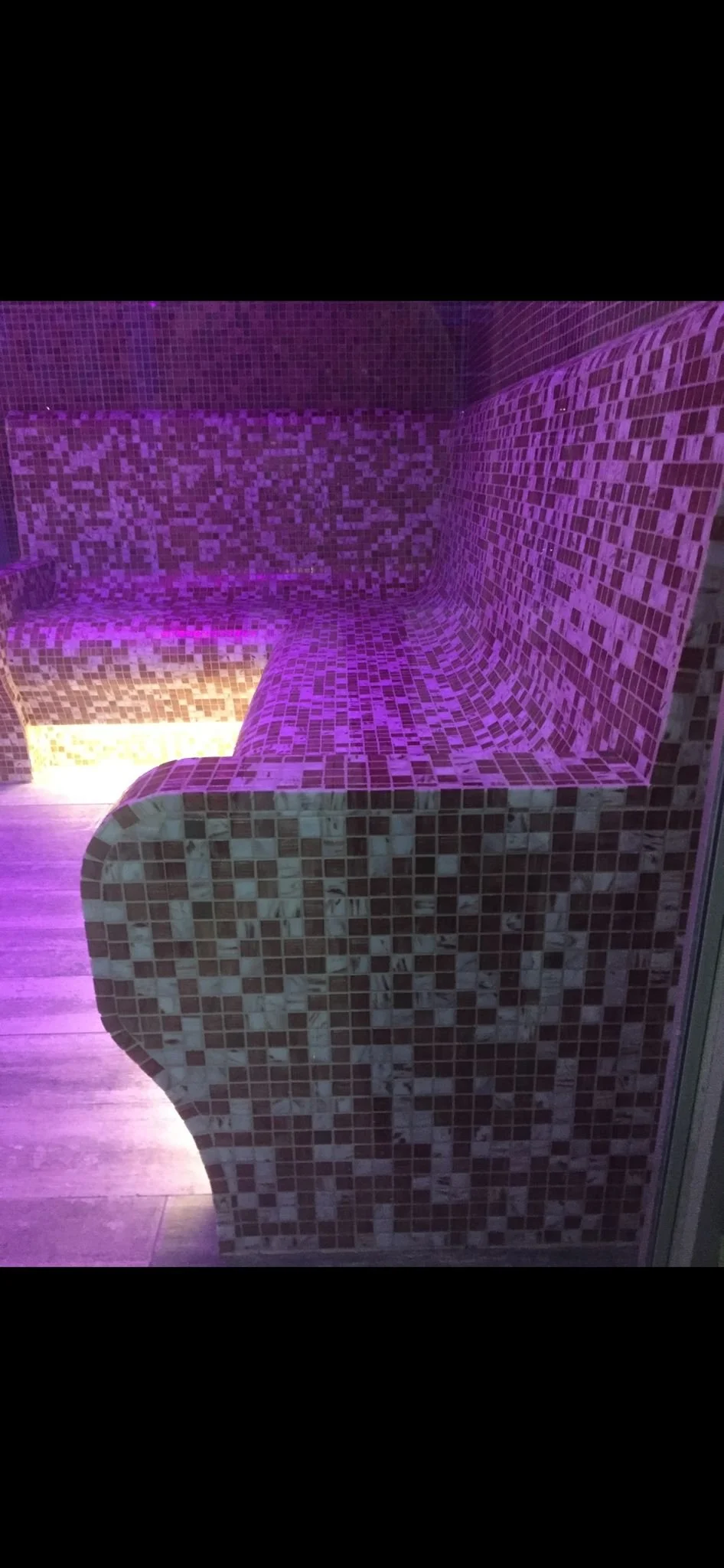 Mosaic tiled seating area illuminated by purple and yellow lights