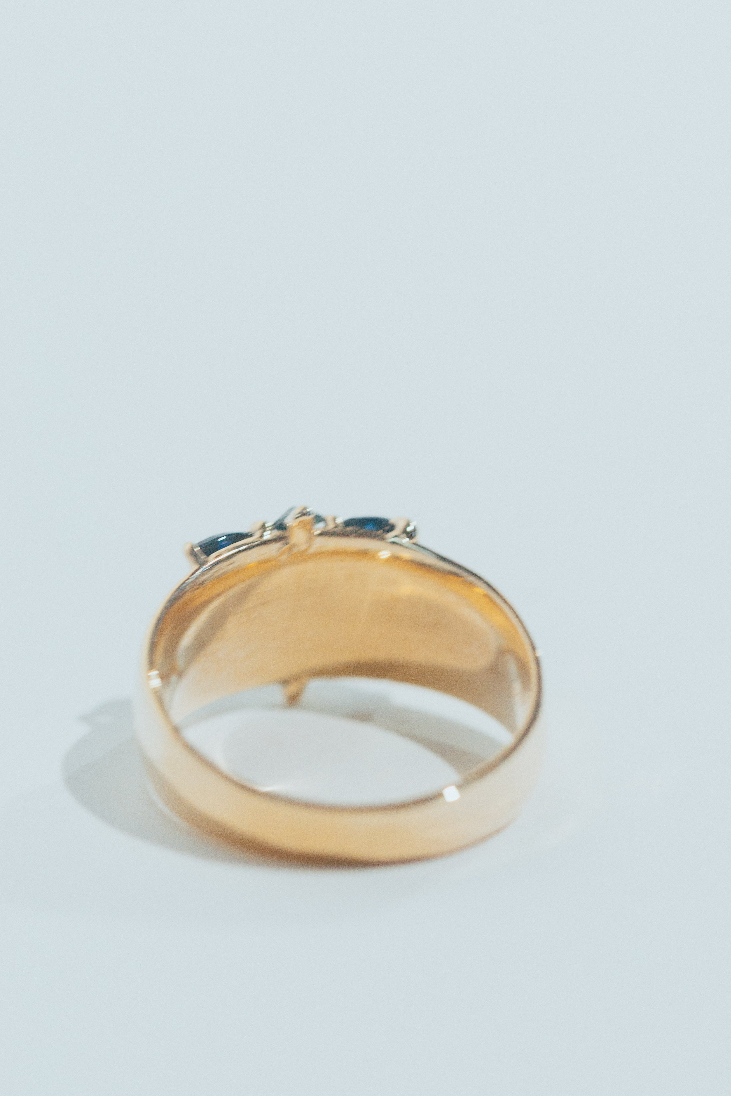 Gold ring with black and silver stones on a white surface.