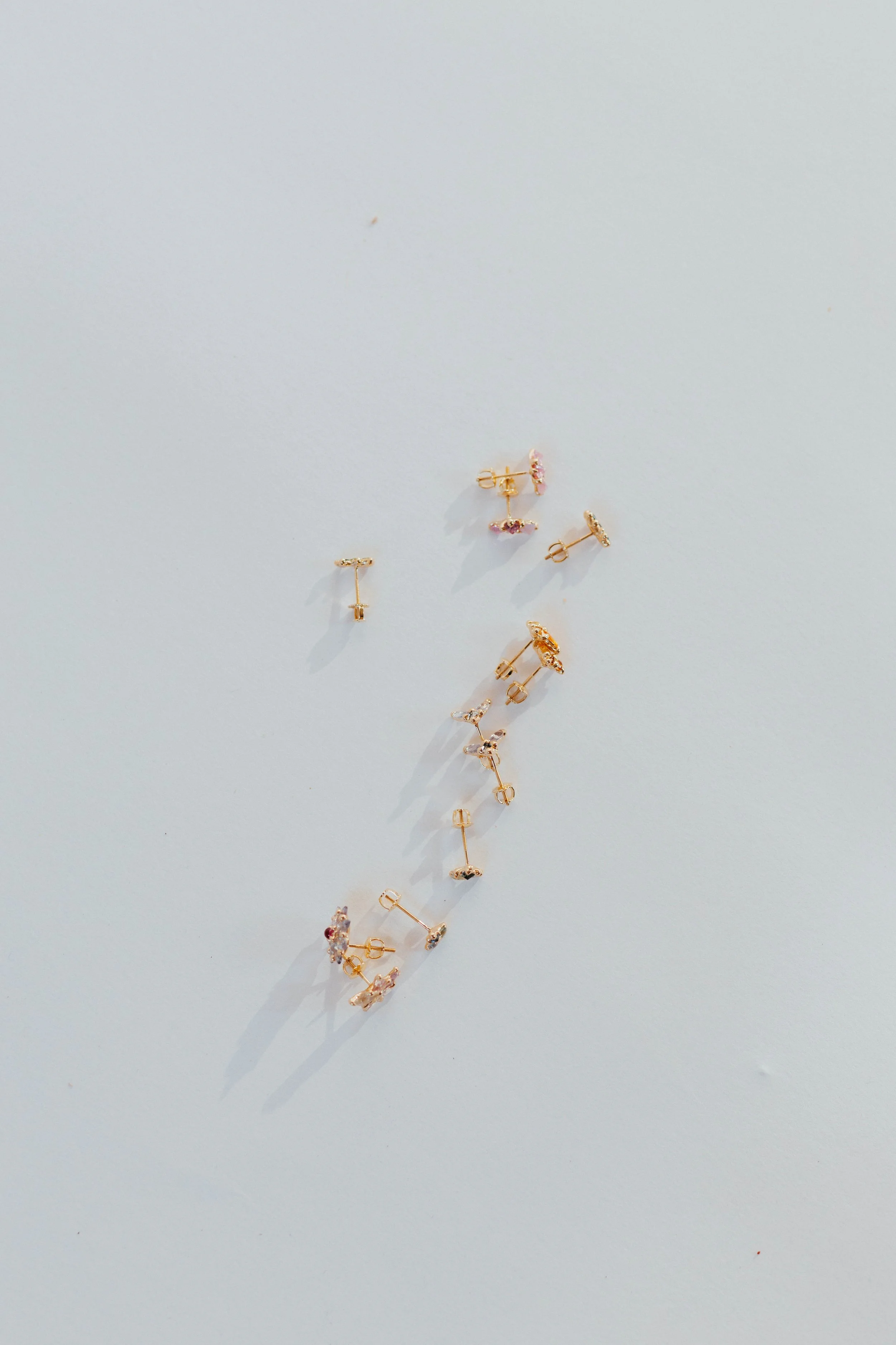 Assorted scattered earrings on a light surface.